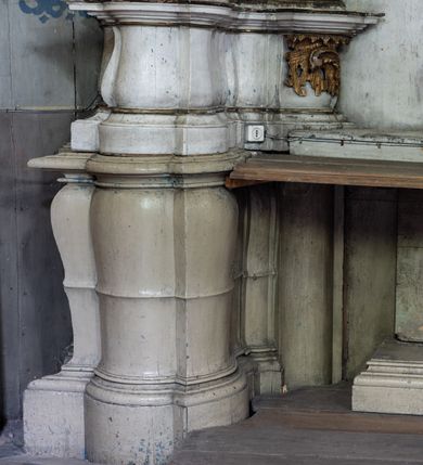 Zdjęcie nr 14: Przyścienny ołtarz Najświętszego Serca Pana Jezusa uzyskał formę architektonicznej nastawy jednokondygnacyjnej, jednoosiowej ze zwieńczeniem. Drewniana mensa z portatylem flankowana przez dwustrefowy wklęsło-wypukły cokół retabulum pierwotnie wspierała się na ażurowym, konsolowym stipesie ołtarzowym, dekorowanym ornamentami rocalliowymi. Kondygnacja wsparta na dwustrefowym cokole została ujęta dwiema parami pilastrów zwróconych delikatnie do wewnątrz oraz silnie wysuniętą do przodu parą kolumn o kapitelach kompozytowych. Podpory dźwigają belkowanie o wklęsło-wypukłej linii. Nad polem środkowym belkowanie jest przerwane, a na osiach podpór wyłamane. Na przedłużeniu kolumn na belkowaniu usytuowano wolutowe przyczółki dekorowane rocalliem, stanowiących postumenty do skradzionych figur aniołów. W polu środkowym umieszczono obraz Najświętszego Serca Pana Jezusa, ujęty profilowaną, złoconą ramą w formie stojącego prostokąta zamkniętego łukiem półkolistym nadwieszonym z uskokiem. Poniżej obrazu pomiędzy dwiema rocalliowymi konsolami widnieje zdjęcie obrazu św. Katarzyny Aleksandryjskiej. Zwieńczenie uzyskało formę leżącego prostokąta o wklęsłych, wolutowych bokach przechodzących u góry we wklęsło-wypukłe belkowanie, przyjmujące nad polem formę łuku falistego. W polu zwieńczenia znalazło się zdjęcie obrazu ze św. Sebastianem ujęte we wklęsło-wypukłą, profilowaną i złoconą ramę. Na szczycie w rocalliowym kartuszu wyobrażono złocony chrystogram "IHS" w srebrnym polu. Pilastry kondygnacji ozdobiono kapitelami z rocaille, a ich trzony udekorowano złoconymi zwisami utworzonymi z rocaille, rozet i liści. Całość struktury polichromowano na biało, a ornamenty i profile zostały wyzłocone. 