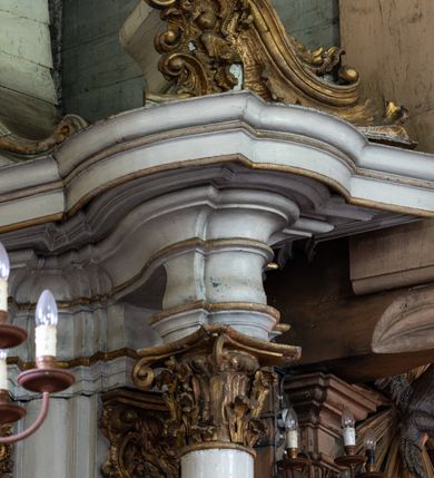 Zdjęcie nr 8: Przyścienny ołtarz Najświętszego Serca Pana Jezusa uzyskał formę architektonicznej nastawy jednokondygnacyjnej, jednoosiowej ze zwieńczeniem. Drewniana mensa z portatylem flankowana przez dwustrefowy wklęsło-wypukły cokół retabulum pierwotnie wspierała się na ażurowym, konsolowym stipesie ołtarzowym, dekorowanym ornamentami rocalliowymi. Kondygnacja wsparta na dwustrefowym cokole została ujęta dwiema parami pilastrów zwróconych delikatnie do wewnątrz oraz silnie wysuniętą do przodu parą kolumn o kapitelach kompozytowych. Podpory dźwigają belkowanie o wklęsło-wypukłej linii. Nad polem środkowym belkowanie jest przerwane, a na osiach podpór wyłamane. Na przedłużeniu kolumn na belkowaniu usytuowano wolutowe przyczółki dekorowane rocalliem, stanowiących postumenty do skradzionych figur aniołów. W polu środkowym umieszczono obraz Najświętszego Serca Pana Jezusa, ujęty profilowaną, złoconą ramą w formie stojącego prostokąta zamkniętego łukiem półkolistym nadwieszonym z uskokiem. Poniżej obrazu pomiędzy dwiema rocalliowymi konsolami widnieje zdjęcie obrazu św. Katarzyny Aleksandryjskiej. Zwieńczenie uzyskało formę leżącego prostokąta o wklęsłych, wolutowych bokach przechodzących u góry we wklęsło-wypukłe belkowanie, przyjmujące nad polem formę łuku falistego. W polu zwieńczenia znalazło się zdjęcie obrazu ze św. Sebastianem ujęte we wklęsło-wypukłą, profilowaną i złoconą ramę. Na szczycie w rocalliowym kartuszu wyobrażono złocony chrystogram "IHS" w srebrnym polu. Pilastry kondygnacji ozdobiono kapitelami z rocaille, a ich trzony udekorowano złoconymi zwisami utworzonymi z rocaille, rozet i liści. Całość struktury polichromowano na biało, a ornamenty i profile zostały wyzłocone. 