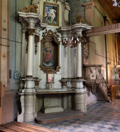 Zdjęcie nr 2: Przyścienny ołtarz Najświętszego Serca Pana Jezusa uzyskał formę architektonicznej nastawy jednokondygnacyjnej, jednoosiowej ze zwieńczeniem. Drewniana mensa z portatylem flankowana przez dwustrefowy wklęsło-wypukły cokół retabulum pierwotnie wspierała się na ażurowym, konsolowym stipesie ołtarzowym, dekorowanym ornamentami rocalliowymi. Kondygnacja wsparta na dwustrefowym cokole została ujęta dwiema parami pilastrów zwróconych delikatnie do wewnątrz oraz silnie wysuniętą do przodu parą kolumn o kapitelach kompozytowych. Podpory dźwigają belkowanie o wklęsło-wypukłej linii. Nad polem środkowym belkowanie jest przerwane, a na osiach podpór wyłamane. Na przedłużeniu kolumn na belkowaniu usytuowano wolutowe przyczółki dekorowane rocalliem, stanowiących postumenty do skradzionych figur aniołów. W polu środkowym umieszczono obraz Najświętszego Serca Pana Jezusa, ujęty profilowaną, złoconą ramą w formie stojącego prostokąta zamkniętego łukiem półkolistym nadwieszonym z uskokiem. Poniżej obrazu pomiędzy dwiema rocalliowymi konsolami widnieje zdjęcie obrazu św. Katarzyny Aleksandryjskiej. Zwieńczenie uzyskało formę leżącego prostokąta o wklęsłych, wolutowych bokach przechodzących u góry we wklęsło-wypukłe belkowanie, przyjmujące nad polem formę łuku falistego. W polu zwieńczenia znalazło się zdjęcie obrazu ze św. Sebastianem ujęte we wklęsło-wypukłą, profilowaną i złoconą ramę. Na szczycie w rocalliowym kartuszu wyobrażono złocony chrystogram "IHS" w srebrnym polu. Pilastry kondygnacji ozdobiono kapitelami z rocaille, a ich trzony udekorowano złoconymi zwisami utworzonymi z rocaille, rozet i liści. Całość struktury polichromowano na biało, a ornamenty i profile zostały wyzłocone. 