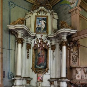 Zdjęcie nr 1: Przyścienny ołtarz Najświętszego Serca Pana Jezusa uzyskał formę architektonicznej nastawy jednokondygnacyjnej, jednoosiowej ze zwieńczeniem. Drewniana mensa z portatylem flankowana przez dwustrefowy wklęsło-wypukły cokół retabulum pierwotnie wspierała się na ażurowym, konsolowym stipesie ołtarzowym, dekorowanym ornamentami rocalliowymi. Kondygnacja wsparta na dwustrefowym cokole została ujęta dwiema parami pilastrów zwróconych delikatnie do wewnątrz oraz silnie wysuniętą do przodu parą kolumn o kapitelach kompozytowych. Podpory dźwigają belkowanie o wklęsło-wypukłej linii. Nad polem środkowym belkowanie jest przerwane, a na osiach podpór wyłamane. Na przedłużeniu kolumn na belkowaniu usytuowano wolutowe przyczółki dekorowane rocalliem, stanowiących postumenty do skradzionych figur aniołów. W polu środkowym umieszczono obraz Najświętszego Serca Pana Jezusa, ujęty profilowaną, złoconą ramą w formie stojącego prostokąta zamkniętego łukiem półkolistym nadwieszonym z uskokiem. Poniżej obrazu pomiędzy dwiema rocalliowymi konsolami widnieje zdjęcie obrazu św. Katarzyny Aleksandryjskiej. Zwieńczenie uzyskało formę leżącego prostokąta o wklęsłych, wolutowych bokach przechodzących u góry we wklęsło-wypukłe belkowanie, przyjmujące nad polem formę łuku falistego. W polu zwieńczenia znalazło się zdjęcie obrazu ze św. Sebastianem ujęte we wklęsło-wypukłą, profilowaną i złoconą ramę. Na szczycie w rocalliowym kartuszu wyobrażono złocony chrystogram "IHS" w srebrnym polu. Pilastry kondygnacji ozdobiono kapitelami z rocaille, a ich trzony udekorowano złoconymi zwisami utworzonymi z rocaille, rozet i liści. Całość struktury polichromowano na biało, a ornamenty i profile zostały wyzłocone. 