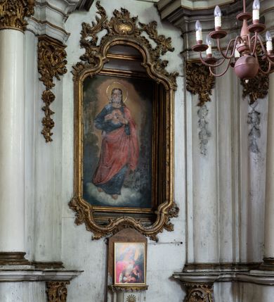 Zdjęcie nr 3: Przyścienny ołtarz Najświętszego Serca Pana Jezusa uzyskał formę architektonicznej nastawy jednokondygnacyjnej, jednoosiowej ze zwieńczeniem. Drewniana mensa z portatylem flankowana przez dwustrefowy wklęsło-wypukły cokół retabulum pierwotnie wspierała się na ażurowym, konsolowym stipesie ołtarzowym, dekorowanym ornamentami rocalliowymi. Kondygnacja wsparta na dwustrefowym cokole została ujęta dwiema parami pilastrów zwróconych delikatnie do wewnątrz oraz silnie wysuniętą do przodu parą kolumn o kapitelach kompozytowych. Podpory dźwigają belkowanie o wklęsło-wypukłej linii. Nad polem środkowym belkowanie jest przerwane, a na osiach podpór wyłamane. Na przedłużeniu kolumn na belkowaniu usytuowano wolutowe przyczółki dekorowane rocalliem, stanowiących postumenty do skradzionych figur aniołów. W polu środkowym umieszczono obraz Najświętszego Serca Pana Jezusa, ujęty profilowaną, złoconą ramą w formie stojącego prostokąta zamkniętego łukiem półkolistym nadwieszonym z uskokiem. Poniżej obrazu pomiędzy dwiema rocalliowymi konsolami widnieje zdjęcie obrazu św. Katarzyny Aleksandryjskiej. Zwieńczenie uzyskało formę leżącego prostokąta o wklęsłych, wolutowych bokach przechodzących u góry we wklęsło-wypukłe belkowanie, przyjmujące nad polem formę łuku falistego. W polu zwieńczenia znalazło się zdjęcie obrazu ze św. Sebastianem ujęte we wklęsło-wypukłą, profilowaną i złoconą ramę. Na szczycie w rocalliowym kartuszu wyobrażono złocony chrystogram "IHS" w srebrnym polu. Pilastry kondygnacji ozdobiono kapitelami z rocaille, a ich trzony udekorowano złoconymi zwisami utworzonymi z rocaille, rozet i liści. Całość struktury polichromowano na biało, a ornamenty i profile zostały wyzłocone. 