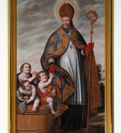 Zdjęcie nr 11: Kamienny ołtarz zamknięto w drewnianej obudowie, nakrywając go drewnianą mensą z portatylem. Stipes ołtarzowy uzyskał kształt prostopadłościanu. Antepedium ujęte zostało złoconą ramą dekorowaną rocaille’m. W jego polu umieszczono haftowaną tkaninę z medalionem w centrum z przedstawieniem w glorii chrystogramu &quot;IHS&quot;, flankowany przez wić różaną. Na mensie ołtarza usytuowano tabernakulum w formie stojącego prostopadłościanu o płaskim froncie i wklęsłych bokach pozbawionych cokołu. Drzwiczki wprawiono w płaską niszę zwieńczoną profilowanym łukiem odcinkowym, nadwieszonym. U góry tabernakulum flankuje para sakramentek. Na tabernakulum usytuowano tron eucharystyczny utworzony z dwóch ażurowych spływów wolutowych podtrzymujących baldachim z lambrekinem. Na baldachimie na czerwonej poduszce spoczywa płaska, złocona korona otwarta. Retabulum ołtarzowe wzniesiono na planie półowalu i polichromowano je na biało. Jest to architektoniczna, jednokondygnacyjna, jednoosiowa struktura ze zwieńczeniem. Po bokach flankują ją bramki ustawione na dwustrefowym, tralkowym, wklęsło-wypukłym cokole. Łuki bramek tworzą fantazyjnie wygięte dwie woluty. Kondygnacja została ujęta dwiema parami pilastrów zwróconych delikatnie do wewnątrz oraz silnie wysuniętą do przodu parą kolumn o kapitelach kompozytowych. Podpory dźwigają pełne belkowanie o wklęsło-wypukłej linii. Nad polem środkowym belkowanie jest połączone gzymsem przyjmującym formę łuku falistego i wyłamane na osiach podpór. Kondygnację ujmują spływy wolutowe połączone z łukowato wygiętymi wolutami podtrzymywanymi przez wysokie tralkowe cokoły, tworząc bramki ołtarza. Bramki zwieńczono fantazyjnie wygiętymi impostami podtrzymującymi ornament rocalliowy. W polu środkowym umieszczono wielkoformatowe zdjęcie znajdującego się tu pierwotnie obrazu św. Mikołaja, ujęte profilowaną, złoconą ramą w formie stojącego prostokąta zamkniętego łukiem półkolistym nadwieszonym z uskokiem. Zwieńczenie uzyskało formę leżącego prostokąta flankowanego parą pilastrów zwróconych do wewnątrz oraz parą pilastrów zwróconych na zewnątrz, których trzony przechodzą w spływy wolutowe opadające na belkowanie. Pilastry dźwigają niepełne, wklęsło-wypukłe belkowanie przyjmujące nad polem formę łuku falistego. W polu zwieńczenia znalazło się przedstawienie gołębicy Ducha Świętego z ażurowymi promieniami na tle owalnego okna prezbiterium, ujęte w fantazjną, wklęsło-wypukłą, profilowaną i złoconą ramę. Pilastry kondygnacji ozdobiono kapitelami z rocaille, a ich trzony udekorowano złoconymi, rokokowymi panneau ze zwisami utworzonymi z rocaille, rozet i liści. Na ich tle usytuowano pierwotnie figury św. Kazimierza Królewicza i św. Augustyna (obecnie przeniesione do krypty nowego kościoła). Rzeźby stały na górnej strefie cokołu na wspornikach z rocaille. W przyłuczach i na belkowaniu znalazły się ornamenty roślinne. Także trzony pilastrów zwieńczenia dekorowane są złoconymi zwisami z rocaille i kwiatów. Pole wokół promieni z gołębicą Ducha Świętego również ozdobiono fragmentami rocaille. 