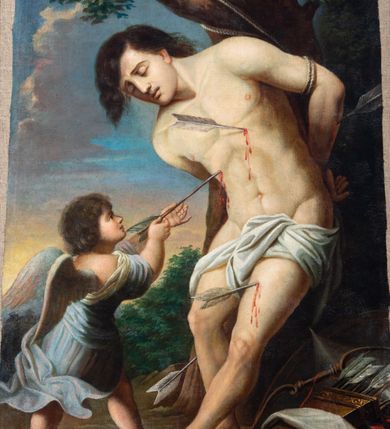 Zdjęcie nr 12: Obraz w formie stojącego prostokąta w drewnianej, profilowanej ramie. W centrum św. Sebastian przywiązany do drzewa, zwrócony w trzech czwartych w prawo, silnie pochylony, z rękami związanymi na plecach, z wysuniętą lewą nogą. Twarz ma wyrazistą, nos długi, usta lekko otwarte, oczy zamknięte, a włosy czarne. Jego nagie ciało przepasane na biodrach jest przebite czterema strzałami. Przed nim stoi anioł, który wyciąga z jego piersi strzałę. Anioł ma twarz pełną, nos krótki, usta drobne, włosy gęste, ciemne, z drobnymi puklami. Ubrany jest w luźną, niebieską suknię, odkrywającą dłonie i plecy oraz nogi. U stóp świętego leży tarcza, kołczan ze strzałami i łuk. W tle widoczne drzewa i krzewy oraz niebo. 