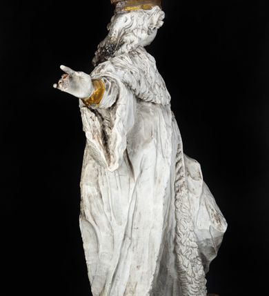 Zdjęcie nr 2: Rzeźba przedstawia całopostaciowe wyobrażenie św. Kazimierza Królewicza. Święty został ukazany w mocnym kontrapoście w trzech czwartych w prawo. Obie uniesione ręce ma odsunięte od tułowia. Kazimierz został ukazany jako młodzieniec o pociągłej twarzy z wydatnym nosem i ustami. Jego głowę otaczają długie, falujące włosy opadające na plecy. Na głowie ma zamkniętą, złoconą koronę z globem i krzyżykiem. Ubrany jest w przewiązaną tunikę i rozwiany, mocno drapowany płaszcz z gronostajowym kołnierzem. Spod tuniki widać nogi obute w złocone trzewiki. Rzeźba w całości polichromowana na biało, ze złoconymi dodatkami.  