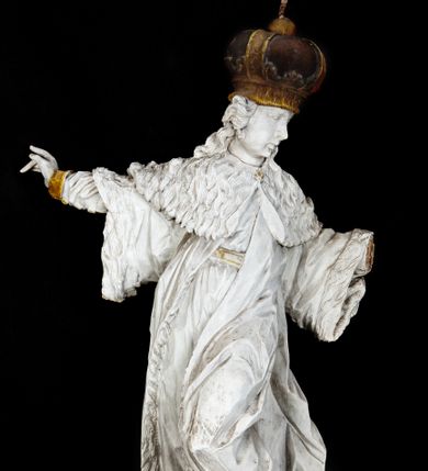 Zdjęcie nr 1: Rzeźba przedstawia całopostaciowe wyobrażenie św. Kazimierza Królewicza. Święty został ukazany w mocnym kontrapoście w trzech czwartych w prawo. Obie uniesione ręce ma odsunięte od tułowia. Kazimierz został ukazany jako młodzieniec o pociągłej twarzy z wydatnym nosem i ustami. Jego głowę otaczają długie, falujące włosy opadające na plecy. Na głowie ma zamkniętą, złoconą koronę z globem i krzyżykiem. Ubrany jest w przewiązaną tunikę i rozwiany, mocno drapowany płaszcz z gronostajowym kołnierzem. Spod tuniki widać nogi obute w złocone trzewiki. Rzeźba w całości polichromowana na biało, ze złoconymi dodatkami.  