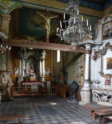 Zdjęcie nr 7: Drewniany kościół pw. św. Mikołaja w Polance jest budowlą orientowaną. Do prostokątnej nawy przylega węższe, wydłużone, trójbocznie zamknięte prezbiterium z piętrową zakrystią na osi o poligonalnym zamknięciu. Do zakrystii przylega od południa kruchta. Fragment północnej ściany prezbiterium jest murowany. Od zachodu do nawy dobudowano czworoboczną wieżę poprzedzoną przedsionkiem, który również dostawiono do nawy od południa. Prezbiterium i nawę wzniesiono na zrąb, natomiast wieżę w konstrukcji słupowej. Wieża na rzucie kwadratu posiada dwie kondygnacje. Dolna jest tej samej szerokości co nawa, górna natomiast znacznie węższa. Jej masyw podzielono smukłymi pilastrami i lizenami, zaś poniżej profilowanego gzymsu koronującego umieszczono wyrzynaną w desce koronkę. Kondygnacje oddzielono daszkiem gontowym zlewającym się po bokach z dachem kościoła. Wieżę nakryto kopulastym hełmem blaszanym, zwieńczonym blaszanym obeliskiem z krzyżem. Prezbiterium i nawę nakryto eternitowym dachem siodłowym podkreślonym profilowanym gzymsem. Nad nawą w części wschodniej zainstalowano wieżyczkę na sygnaturkę w formie wielobocznego graniastosłupa przykrytego cebulastą banią z krzyżem. Dokoła kościoła założono daszek gontowy chroniący podwaliny. Pod kościołem urządzono kryptę grzebalną. Wnętrze kościoła artykułowano za pomocą pilastrów i gzymsu. Całość nakryto stropem z fasetą. Otwór tęczowy uzyskał kształt trójlistnego, ściętego łuku, wspartego na filarkach ustawionych na profilowanej belce zawieszonej na kroksztynach. W części zachodniej nawy urządzono chór muzyczny, wsparty na dwóch kolumnach jońskich z przedpiersiem rozczłonkowanym balasami. We wnętrzu ustawiono ołtarz główny i dwa ołtarze boczne oraz ambonę, a na chórze muzycznym zainstalowano prospekt organowy.