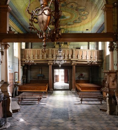 Zdjęcie nr 14: Drewniany kościół pw. św. Mikołaja w Polance jest budowlą orientowaną. Do prostokątnej nawy przylega węższe, wydłużone, trójbocznie zamknięte prezbiterium z piętrową zakrystią na osi o poligonalnym zamknięciu. Do zakrystii przylega od południa kruchta. Fragment północnej ściany prezbiterium jest murowany. Od zachodu do nawy dobudowano czworoboczną wieżę poprzedzoną przedsionkiem, który również dostawiono do nawy od południa. Prezbiterium i nawę wzniesiono na zrąb, natomiast wieżę w konstrukcji słupowej. Wieża na rzucie kwadratu posiada dwie kondygnacje. Dolna jest tej samej szerokości co nawa, górna natomiast znacznie węższa. Jej masyw podzielono smukłymi pilastrami i lizenami, zaś poniżej profilowanego gzymsu koronującego umieszczono wyrzynaną w desce koronkę. Kondygnacje oddzielono daszkiem gontowym zlewającym się po bokach z dachem kościoła. Wieżę nakryto kopulastym hełmem blaszanym, zwieńczonym blaszanym obeliskiem z krzyżem. Prezbiterium i nawę nakryto eternitowym dachem siodłowym podkreślonym profilowanym gzymsem. Nad nawą w części wschodniej zainstalowano wieżyczkę na sygnaturkę w formie wielobocznego graniastosłupa przykrytego cebulastą banią z krzyżem. Dokoła kościoła założono daszek gontowy chroniący podwaliny. Pod kościołem urządzono kryptę grzebalną. Wnętrze kościoła artykułowano za pomocą pilastrów i gzymsu. Całość nakryto stropem z fasetą. Otwór tęczowy uzyskał kształt trójlistnego, ściętego łuku, wspartego na filarkach ustawionych na profilowanej belce zawieszonej na kroksztynach. W części zachodniej nawy urządzono chór muzyczny, wsparty na dwóch kolumnach jońskich z przedpiersiem rozczłonkowanym balasami. We wnętrzu ustawiono ołtarz główny i dwa ołtarze boczne oraz ambonę, a na chórze muzycznym zainstalowano prospekt organowy.