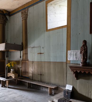 Zdjęcie nr 19: Drewniany kościół pw. św. Mikołaja w Polance jest budowlą orientowaną. Do prostokątnej nawy przylega węższe, wydłużone, trójbocznie zamknięte prezbiterium z piętrową zakrystią na osi o poligonalnym zamknięciu. Do zakrystii przylega od południa kruchta. Fragment północnej ściany prezbiterium jest murowany. Od zachodu do nawy dobudowano czworoboczną wieżę poprzedzoną przedsionkiem, który również dostawiono do nawy od południa. Prezbiterium i nawę wzniesiono na zrąb, natomiast wieżę w konstrukcji słupowej. Wieża na rzucie kwadratu posiada dwie kondygnacje. Dolna jest tej samej szerokości co nawa, górna natomiast znacznie węższa. Jej masyw podzielono smukłymi pilastrami i lizenami, zaś poniżej profilowanego gzymsu koronującego umieszczono wyrzynaną w desce koronkę. Kondygnacje oddzielono daszkiem gontowym zlewającym się po bokach z dachem kościoła. Wieżę nakryto kopulastym hełmem blaszanym, zwieńczonym blaszanym obeliskiem z krzyżem. Prezbiterium i nawę nakryto eternitowym dachem siodłowym podkreślonym profilowanym gzymsem. Nad nawą w części wschodniej zainstalowano wieżyczkę na sygnaturkę w formie wielobocznego graniastosłupa przykrytego cebulastą banią z krzyżem. Dokoła kościoła założono daszek gontowy chroniący podwaliny. Pod kościołem urządzono kryptę grzebalną. Wnętrze kościoła artykułowano za pomocą pilastrów i gzymsu. Całość nakryto stropem z fasetą. Otwór tęczowy uzyskał kształt trójlistnego, ściętego łuku, wspartego na filarkach ustawionych na profilowanej belce zawieszonej na kroksztynach. W części zachodniej nawy urządzono chór muzyczny, wsparty na dwóch kolumnach jońskich z przedpiersiem rozczłonkowanym balasami. We wnętrzu ustawiono ołtarz główny i dwa ołtarze boczne oraz ambonę, a na chórze muzycznym zainstalowano prospekt organowy.