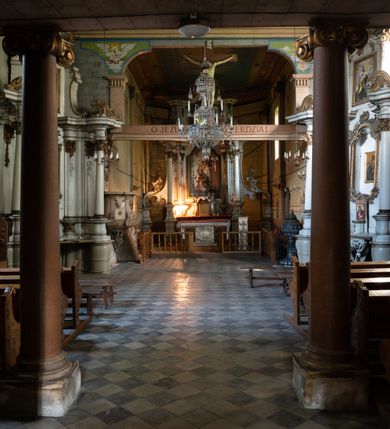 Zdjęcie nr 10: Drewniany kościół pw. św. Mikołaja w Polance jest budowlą orientowaną. Do prostokątnej nawy przylega węższe, wydłużone, trójbocznie zamknięte prezbiterium z piętrową zakrystią na osi o poligonalnym zamknięciu. Do zakrystii przylega od południa kruchta. Fragment północnej ściany prezbiterium jest murowany. Od zachodu do nawy dobudowano czworoboczną wieżę poprzedzoną przedsionkiem, który również dostawiono do nawy od południa. Prezbiterium i nawę wzniesiono na zrąb, natomiast wieżę w konstrukcji słupowej. Wieża na rzucie kwadratu posiada dwie kondygnacje. Dolna jest tej samej szerokości co nawa, górna natomiast znacznie węższa. Jej masyw podzielono smukłymi pilastrami i lizenami, zaś poniżej profilowanego gzymsu koronującego umieszczono wyrzynaną w desce koronkę. Kondygnacje oddzielono daszkiem gontowym zlewającym się po bokach z dachem kościoła. Wieżę nakryto kopulastym hełmem blaszanym, zwieńczonym blaszanym obeliskiem z krzyżem. Prezbiterium i nawę nakryto eternitowym dachem siodłowym podkreślonym profilowanym gzymsem. Nad nawą w części wschodniej zainstalowano wieżyczkę na sygnaturkę w formie wielobocznego graniastosłupa przykrytego cebulastą banią z krzyżem. Dokoła kościoła założono daszek gontowy chroniący podwaliny. Pod kościołem urządzono kryptę grzebalną. Wnętrze kościoła artykułowano za pomocą pilastrów i gzymsu. Całość nakryto stropem z fasetą. Otwór tęczowy uzyskał kształt trójlistnego, ściętego łuku, wspartego na filarkach ustawionych na profilowanej belce zawieszonej na kroksztynach. W części zachodniej nawy urządzono chór muzyczny, wsparty na dwóch kolumnach jońskich z przedpiersiem rozczłonkowanym balasami. We wnętrzu ustawiono ołtarz główny i dwa ołtarze boczne oraz ambonę, a na chórze muzycznym zainstalowano prospekt organowy.