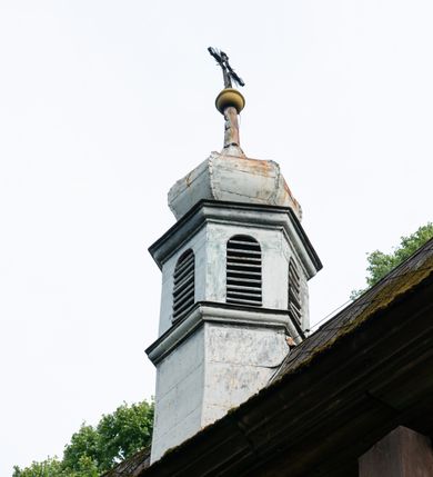 Zdjęcie nr 40: Drewniany kościół pw. św. Mikołaja w Polance jest budowlą orientowaną. Do prostokątnej nawy przylega węższe, wydłużone, trójbocznie zamknięte prezbiterium z piętrową zakrystią na osi o poligonalnym zamknięciu. Do zakrystii przylega od południa kruchta. Fragment północnej ściany prezbiterium jest murowany. Od zachodu do nawy dobudowano czworoboczną wieżę poprzedzoną przedsionkiem, który również dostawiono do nawy od południa. Prezbiterium i nawę wzniesiono na zrąb, natomiast wieżę w konstrukcji słupowej. Wieża na rzucie kwadratu posiada dwie kondygnacje. Dolna jest tej samej szerokości co nawa, górna natomiast znacznie węższa. Jej masyw podzielono smukłymi pilastrami i lizenami, zaś poniżej profilowanego gzymsu koronującego umieszczono wyrzynaną w desce koronkę. Kondygnacje oddzielono daszkiem gontowym zlewającym się po bokach z dachem kościoła. Wieżę nakryto kopulastym hełmem blaszanym, zwieńczonym blaszanym obeliskiem z krzyżem. Prezbiterium i nawę nakryto eternitowym dachem siodłowym podkreślonym profilowanym gzymsem. Nad nawą w części wschodniej zainstalowano wieżyczkę na sygnaturkę w formie wielobocznego graniastosłupa przykrytego cebulastą banią z krzyżem. Dokoła kościoła założono daszek gontowy chroniący podwaliny. Pod kościołem urządzono kryptę grzebalną. Wnętrze kościoła artykułowano za pomocą pilastrów i gzymsu. Całość nakryto stropem z fasetą. Otwór tęczowy uzyskał kształt trójlistnego, ściętego łuku, wspartego na filarkach ustawionych na profilowanej belce zawieszonej na kroksztynach. W części zachodniej nawy urządzono chór muzyczny, wsparty na dwóch kolumnach jońskich z przedpiersiem rozczłonkowanym balasami. We wnętrzu ustawiono ołtarz główny i dwa ołtarze boczne oraz ambonę, a na chórze muzycznym zainstalowano prospekt organowy.