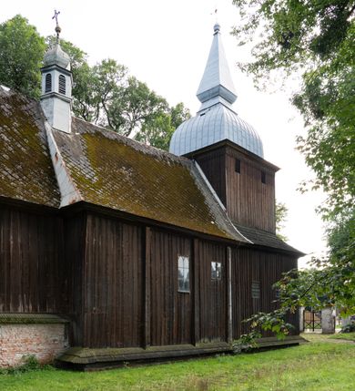 Zdjęcie nr 36: Drewniany kościół pw. św. Mikołaja w Polance jest budowlą orientowaną. Do prostokątnej nawy przylega węższe, wydłużone, trójbocznie zamknięte prezbiterium z piętrową zakrystią na osi o poligonalnym zamknięciu. Do zakrystii przylega od południa kruchta. Fragment północnej ściany prezbiterium jest murowany. Od zachodu do nawy dobudowano czworoboczną wieżę poprzedzoną przedsionkiem, który również dostawiono do nawy od południa. Prezbiterium i nawę wzniesiono na zrąb, natomiast wieżę w konstrukcji słupowej. Wieża na rzucie kwadratu posiada dwie kondygnacje. Dolna jest tej samej szerokości co nawa, górna natomiast znacznie węższa. Jej masyw podzielono smukłymi pilastrami i lizenami, zaś poniżej profilowanego gzymsu koronującego umieszczono wyrzynaną w desce koronkę. Kondygnacje oddzielono daszkiem gontowym zlewającym się po bokach z dachem kościoła. Wieżę nakryto kopulastym hełmem blaszanym, zwieńczonym blaszanym obeliskiem z krzyżem. Prezbiterium i nawę nakryto eternitowym dachem siodłowym podkreślonym profilowanym gzymsem. Nad nawą w części wschodniej zainstalowano wieżyczkę na sygnaturkę w formie wielobocznego graniastosłupa przykrytego cebulastą banią z krzyżem. Dokoła kościoła założono daszek gontowy chroniący podwaliny. Pod kościołem urządzono kryptę grzebalną. Wnętrze kościoła artykułowano za pomocą pilastrów i gzymsu. Całość nakryto stropem z fasetą. Otwór tęczowy uzyskał kształt trójlistnego, ściętego łuku, wspartego na filarkach ustawionych na profilowanej belce zawieszonej na kroksztynach. W części zachodniej nawy urządzono chór muzyczny, wsparty na dwóch kolumnach jońskich z przedpiersiem rozczłonkowanym balasami. We wnętrzu ustawiono ołtarz główny i dwa ołtarze boczne oraz ambonę, a na chórze muzycznym zainstalowano prospekt organowy.
