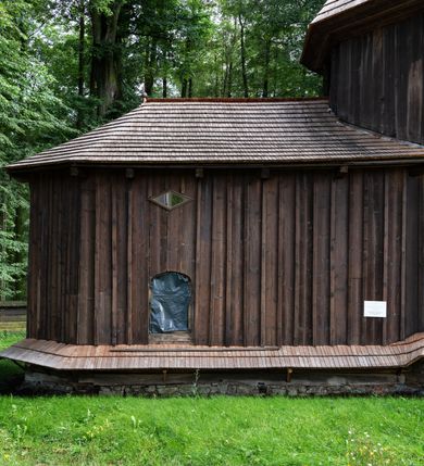 Zdjęcie nr 37: Drewniany kościół pw. św. Mikołaja w Polance jest budowlą orientowaną. Do prostokątnej nawy przylega węższe, wydłużone, trójbocznie zamknięte prezbiterium z piętrową zakrystią na osi o poligonalnym zamknięciu. Do zakrystii przylega od południa kruchta. Fragment północnej ściany prezbiterium jest murowany. Od zachodu do nawy dobudowano czworoboczną wieżę poprzedzoną przedsionkiem, który również dostawiono do nawy od południa. Prezbiterium i nawę wzniesiono na zrąb, natomiast wieżę w konstrukcji słupowej. Wieża na rzucie kwadratu posiada dwie kondygnacje. Dolna jest tej samej szerokości co nawa, górna natomiast znacznie węższa. Jej masyw podzielono smukłymi pilastrami i lizenami, zaś poniżej profilowanego gzymsu koronującego umieszczono wyrzynaną w desce koronkę. Kondygnacje oddzielono daszkiem gontowym zlewającym się po bokach z dachem kościoła. Wieżę nakryto kopulastym hełmem blaszanym, zwieńczonym blaszanym obeliskiem z krzyżem. Prezbiterium i nawę nakryto eternitowym dachem siodłowym podkreślonym profilowanym gzymsem. Nad nawą w części wschodniej zainstalowano wieżyczkę na sygnaturkę w formie wielobocznego graniastosłupa przykrytego cebulastą banią z krzyżem. Dokoła kościoła założono daszek gontowy chroniący podwaliny. Pod kościołem urządzono kryptę grzebalną. Wnętrze kościoła artykułowano za pomocą pilastrów i gzymsu. Całość nakryto stropem z fasetą. Otwór tęczowy uzyskał kształt trójlistnego, ściętego łuku, wspartego na filarkach ustawionych na profilowanej belce zawieszonej na kroksztynach. W części zachodniej nawy urządzono chór muzyczny, wsparty na dwóch kolumnach jońskich z przedpiersiem rozczłonkowanym balasami. We wnętrzu ustawiono ołtarz główny i dwa ołtarze boczne oraz ambonę, a na chórze muzycznym zainstalowano prospekt organowy.