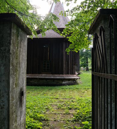 Zdjęcie nr 62: Drewniany kościół pw. św. Mikołaja w Polance jest budowlą orientowaną. Do prostokątnej nawy przylega węższe, wydłużone, trójbocznie zamknięte prezbiterium z piętrową zakrystią na osi o poligonalnym zamknięciu. Do zakrystii przylega od południa kruchta. Fragment północnej ściany prezbiterium jest murowany. Od zachodu do nawy dobudowano czworoboczną wieżę poprzedzoną przedsionkiem, który również dostawiono do nawy od południa. Prezbiterium i nawę wzniesiono na zrąb, natomiast wieżę w konstrukcji słupowej. Wieża na rzucie kwadratu posiada dwie kondygnacje. Dolna jest tej samej szerokości co nawa, górna natomiast znacznie węższa. Jej masyw podzielono smukłymi pilastrami i lizenami, zaś poniżej profilowanego gzymsu koronującego umieszczono wyrzynaną w desce koronkę. Kondygnacje oddzielono daszkiem gontowym zlewającym się po bokach z dachem kościoła. Wieżę nakryto kopulastym hełmem blaszanym, zwieńczonym blaszanym obeliskiem z krzyżem. Prezbiterium i nawę nakryto eternitowym dachem siodłowym podkreślonym profilowanym gzymsem. Nad nawą w części wschodniej zainstalowano wieżyczkę na sygnaturkę w formie wielobocznego graniastosłupa przykrytego cebulastą banią z krzyżem. Dokoła kościoła założono daszek gontowy chroniący podwaliny. Pod kościołem urządzono kryptę grzebalną. Wnętrze kościoła artykułowano za pomocą pilastrów i gzymsu. Całość nakryto stropem z fasetą. Otwór tęczowy uzyskał kształt trójlistnego, ściętego łuku, wspartego na filarkach ustawionych na profilowanej belce zawieszonej na kroksztynach. W części zachodniej nawy urządzono chór muzyczny, wsparty na dwóch kolumnach jońskich z przedpiersiem rozczłonkowanym balasami. We wnętrzu ustawiono ołtarz główny i dwa ołtarze boczne oraz ambonę, a na chórze muzycznym zainstalowano prospekt organowy.