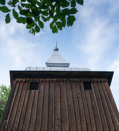 Zdjęcie nr 29: Drewniany kościół pw. św. Mikołaja w Polance jest budowlą orientowaną. Do prostokątnej nawy przylega węższe, wydłużone, trójbocznie zamknięte prezbiterium z piętrową zakrystią na osi o poligonalnym zamknięciu. Do zakrystii przylega od południa kruchta. Fragment północnej ściany prezbiterium jest murowany. Od zachodu do nawy dobudowano czworoboczną wieżę poprzedzoną przedsionkiem, który również dostawiono do nawy od południa. Prezbiterium i nawę wzniesiono na zrąb, natomiast wieżę w konstrukcji słupowej. Wieża na rzucie kwadratu posiada dwie kondygnacje. Dolna jest tej samej szerokości co nawa, górna natomiast znacznie węższa. Jej masyw podzielono smukłymi pilastrami i lizenami, zaś poniżej profilowanego gzymsu koronującego umieszczono wyrzynaną w desce koronkę. Kondygnacje oddzielono daszkiem gontowym zlewającym się po bokach z dachem kościoła. Wieżę nakryto kopulastym hełmem blaszanym, zwieńczonym blaszanym obeliskiem z krzyżem. Prezbiterium i nawę nakryto eternitowym dachem siodłowym podkreślonym profilowanym gzymsem. Nad nawą w części wschodniej zainstalowano wieżyczkę na sygnaturkę w formie wielobocznego graniastosłupa przykrytego cebulastą banią z krzyżem. Dokoła kościoła założono daszek gontowy chroniący podwaliny. Pod kościołem urządzono kryptę grzebalną. Wnętrze kościoła artykułowano za pomocą pilastrów i gzymsu. Całość nakryto stropem z fasetą. Otwór tęczowy uzyskał kształt trójlistnego, ściętego łuku, wspartego na filarkach ustawionych na profilowanej belce zawieszonej na kroksztynach. W części zachodniej nawy urządzono chór muzyczny, wsparty na dwóch kolumnach jońskich z przedpiersiem rozczłonkowanym balasami. We wnętrzu ustawiono ołtarz główny i dwa ołtarze boczne oraz ambonę, a na chórze muzycznym zainstalowano prospekt organowy.