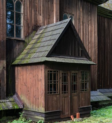 Zdjęcie nr 57: Drewniany kościół pw. św. Mikołaja w Polance jest budowlą orientowaną. Do prostokątnej nawy przylega węższe, wydłużone, trójbocznie zamknięte prezbiterium z piętrową zakrystią na osi o poligonalnym zamknięciu. Do zakrystii przylega od południa kruchta. Fragment północnej ściany prezbiterium jest murowany. Od zachodu do nawy dobudowano czworoboczną wieżę poprzedzoną przedsionkiem, który również dostawiono do nawy od południa. Prezbiterium i nawę wzniesiono na zrąb, natomiast wieżę w konstrukcji słupowej. Wieża na rzucie kwadratu posiada dwie kondygnacje. Dolna jest tej samej szerokości co nawa, górna natomiast znacznie węższa. Jej masyw podzielono smukłymi pilastrami i lizenami, zaś poniżej profilowanego gzymsu koronującego umieszczono wyrzynaną w desce koronkę. Kondygnacje oddzielono daszkiem gontowym zlewającym się po bokach z dachem kościoła. Wieżę nakryto kopulastym hełmem blaszanym, zwieńczonym blaszanym obeliskiem z krzyżem. Prezbiterium i nawę nakryto eternitowym dachem siodłowym podkreślonym profilowanym gzymsem. Nad nawą w części wschodniej zainstalowano wieżyczkę na sygnaturkę w formie wielobocznego graniastosłupa przykrytego cebulastą banią z krzyżem. Dokoła kościoła założono daszek gontowy chroniący podwaliny. Pod kościołem urządzono kryptę grzebalną. Wnętrze kościoła artykułowano za pomocą pilastrów i gzymsu. Całość nakryto stropem z fasetą. Otwór tęczowy uzyskał kształt trójlistnego, ściętego łuku, wspartego na filarkach ustawionych na profilowanej belce zawieszonej na kroksztynach. W części zachodniej nawy urządzono chór muzyczny, wsparty na dwóch kolumnach jońskich z przedpiersiem rozczłonkowanym balasami. We wnętrzu ustawiono ołtarz główny i dwa ołtarze boczne oraz ambonę, a na chórze muzycznym zainstalowano prospekt organowy.