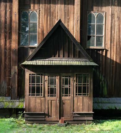 Zdjęcie nr 58: Drewniany kościół pw. św. Mikołaja w Polance jest budowlą orientowaną. Do prostokątnej nawy przylega węższe, wydłużone, trójbocznie zamknięte prezbiterium z piętrową zakrystią na osi o poligonalnym zamknięciu. Do zakrystii przylega od południa kruchta. Fragment północnej ściany prezbiterium jest murowany. Od zachodu do nawy dobudowano czworoboczną wieżę poprzedzoną przedsionkiem, który również dostawiono do nawy od południa. Prezbiterium i nawę wzniesiono na zrąb, natomiast wieżę w konstrukcji słupowej. Wieża na rzucie kwadratu posiada dwie kondygnacje. Dolna jest tej samej szerokości co nawa, górna natomiast znacznie węższa. Jej masyw podzielono smukłymi pilastrami i lizenami, zaś poniżej profilowanego gzymsu koronującego umieszczono wyrzynaną w desce koronkę. Kondygnacje oddzielono daszkiem gontowym zlewającym się po bokach z dachem kościoła. Wieżę nakryto kopulastym hełmem blaszanym, zwieńczonym blaszanym obeliskiem z krzyżem. Prezbiterium i nawę nakryto eternitowym dachem siodłowym podkreślonym profilowanym gzymsem. Nad nawą w części wschodniej zainstalowano wieżyczkę na sygnaturkę w formie wielobocznego graniastosłupa przykrytego cebulastą banią z krzyżem. Dokoła kościoła założono daszek gontowy chroniący podwaliny. Pod kościołem urządzono kryptę grzebalną. Wnętrze kościoła artykułowano za pomocą pilastrów i gzymsu. Całość nakryto stropem z fasetą. Otwór tęczowy uzyskał kształt trójlistnego, ściętego łuku, wspartego na filarkach ustawionych na profilowanej belce zawieszonej na kroksztynach. W części zachodniej nawy urządzono chór muzyczny, wsparty na dwóch kolumnach jońskich z przedpiersiem rozczłonkowanym balasami. We wnętrzu ustawiono ołtarz główny i dwa ołtarze boczne oraz ambonę, a na chórze muzycznym zainstalowano prospekt organowy.