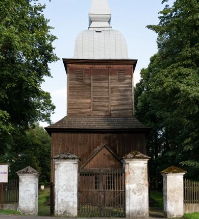 Zdjęcie nr 1: Drewniany kościół pw. św. Mikołaja w Polance jest budowlą orientowaną. Do prostokątnej nawy przylega węższe, wydłużone, trójbocznie zamknięte prezbiterium z piętrową zakrystią na osi o poligonalnym zamknięciu. Do zakrystii przylega od południa kruchta. Fragment północnej ściany prezbiterium jest murowany. Od zachodu do nawy dobudowano czworoboczną wieżę poprzedzoną przedsionkiem, który również dostawiono do nawy od południa. Prezbiterium i nawę wzniesiono na zrąb, natomiast wieżę w konstrukcji słupowej. Wieża na rzucie kwadratu posiada dwie kondygnacje. Dolna jest tej samej szerokości co nawa, górna natomiast znacznie węższa. Jej masyw podzielono smukłymi pilastrami i lizenami, zaś poniżej profilowanego gzymsu koronującego umieszczono wyrzynaną w desce koronkę. Kondygnacje oddzielono daszkiem gontowym zlewającym się po bokach z dachem kościoła. Wieżę nakryto kopulastym hełmem blaszanym, zwieńczonym blaszanym obeliskiem z krzyżem. Prezbiterium i nawę nakryto eternitowym dachem siodłowym podkreślonym profilowanym gzymsem. Nad nawą w części wschodniej zainstalowano wieżyczkę na sygnaturkę w formie wielobocznego graniastosłupa przykrytego cebulastą banią z krzyżem. Dokoła kościoła założono daszek gontowy chroniący podwaliny. Pod kościołem urządzono kryptę grzebalną. Wnętrze kościoła artykułowano za pomocą pilastrów i gzymsu. Całość nakryto stropem z fasetą. Otwór tęczowy uzyskał kształt trójlistnego, ściętego łuku, wspartego na filarkach ustawionych na profilowanej belce zawieszonej na kroksztynach. W części zachodniej nawy urządzono chór muzyczny, wsparty na dwóch kolumnach jońskich z przedpiersiem rozczłonkowanym balasami. We wnętrzu ustawiono ołtarz główny i dwa ołtarze boczne oraz ambonę, a na chórze muzycznym zainstalowano prospekt organowy.