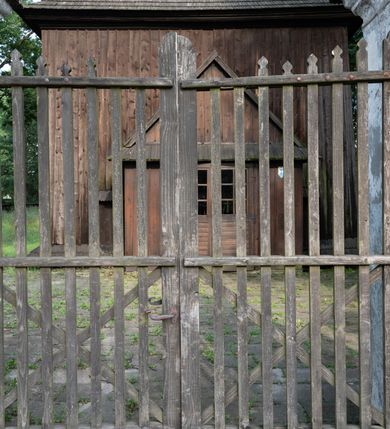 Zdjęcie nr 61: Drewniany kościół pw. św. Mikołaja w Polance jest budowlą orientowaną. Do prostokątnej nawy przylega węższe, wydłużone, trójbocznie zamknięte prezbiterium z piętrową zakrystią na osi o poligonalnym zamknięciu. Do zakrystii przylega od południa kruchta. Fragment północnej ściany prezbiterium jest murowany. Od zachodu do nawy dobudowano czworoboczną wieżę poprzedzoną przedsionkiem, który również dostawiono do nawy od południa. Prezbiterium i nawę wzniesiono na zrąb, natomiast wieżę w konstrukcji słupowej. Wieża na rzucie kwadratu posiada dwie kondygnacje. Dolna jest tej samej szerokości co nawa, górna natomiast znacznie węższa. Jej masyw podzielono smukłymi pilastrami i lizenami, zaś poniżej profilowanego gzymsu koronującego umieszczono wyrzynaną w desce koronkę. Kondygnacje oddzielono daszkiem gontowym zlewającym się po bokach z dachem kościoła. Wieżę nakryto kopulastym hełmem blaszanym, zwieńczonym blaszanym obeliskiem z krzyżem. Prezbiterium i nawę nakryto eternitowym dachem siodłowym podkreślonym profilowanym gzymsem. Nad nawą w części wschodniej zainstalowano wieżyczkę na sygnaturkę w formie wielobocznego graniastosłupa przykrytego cebulastą banią z krzyżem. Dokoła kościoła założono daszek gontowy chroniący podwaliny. Pod kościołem urządzono kryptę grzebalną. Wnętrze kościoła artykułowano za pomocą pilastrów i gzymsu. Całość nakryto stropem z fasetą. Otwór tęczowy uzyskał kształt trójlistnego, ściętego łuku, wspartego na filarkach ustawionych na profilowanej belce zawieszonej na kroksztynach. W części zachodniej nawy urządzono chór muzyczny, wsparty na dwóch kolumnach jońskich z przedpiersiem rozczłonkowanym balasami. We wnętrzu ustawiono ołtarz główny i dwa ołtarze boczne oraz ambonę, a na chórze muzycznym zainstalowano prospekt organowy.