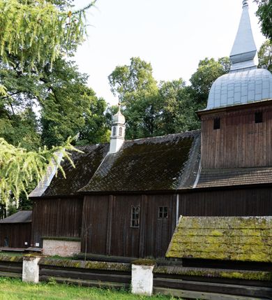 Zdjęcie nr 23: Drewniany kościół pw. św. Mikołaja w Polance jest budowlą orientowaną. Do prostokątnej nawy przylega węższe, wydłużone, trójbocznie zamknięte prezbiterium z piętrową zakrystią na osi o poligonalnym zamknięciu. Do zakrystii przylega od południa kruchta. Fragment północnej ściany prezbiterium jest murowany. Od zachodu do nawy dobudowano czworoboczną wieżę poprzedzoną przedsionkiem, który również dostawiono do nawy od południa. Prezbiterium i nawę wzniesiono na zrąb, natomiast wieżę w konstrukcji słupowej. Wieża na rzucie kwadratu posiada dwie kondygnacje. Dolna jest tej samej szerokości co nawa, górna natomiast znacznie węższa. Jej masyw podzielono smukłymi pilastrami i lizenami, zaś poniżej profilowanego gzymsu koronującego umieszczono wyrzynaną w desce koronkę. Kondygnacje oddzielono daszkiem gontowym zlewającym się po bokach z dachem kościoła. Wieżę nakryto kopulastym hełmem blaszanym, zwieńczonym blaszanym obeliskiem z krzyżem. Prezbiterium i nawę nakryto eternitowym dachem siodłowym podkreślonym profilowanym gzymsem. Nad nawą w części wschodniej zainstalowano wieżyczkę na sygnaturkę w formie wielobocznego graniastosłupa przykrytego cebulastą banią z krzyżem. Dokoła kościoła założono daszek gontowy chroniący podwaliny. Pod kościołem urządzono kryptę grzebalną. Wnętrze kościoła artykułowano za pomocą pilastrów i gzymsu. Całość nakryto stropem z fasetą. Otwór tęczowy uzyskał kształt trójlistnego, ściętego łuku, wspartego na filarkach ustawionych na profilowanej belce zawieszonej na kroksztynach. W części zachodniej nawy urządzono chór muzyczny, wsparty na dwóch kolumnach jońskich z przedpiersiem rozczłonkowanym balasami. We wnętrzu ustawiono ołtarz główny i dwa ołtarze boczne oraz ambonę, a na chórze muzycznym zainstalowano prospekt organowy.