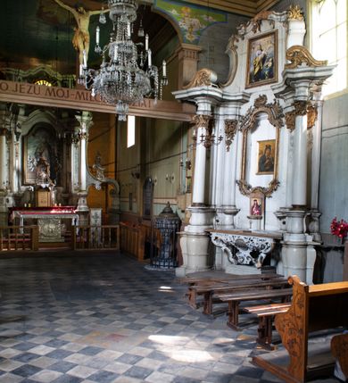 Zdjęcie nr 5: Drewniany kościół pw. św. Mikołaja w Polance jest budowlą orientowaną. Do prostokątnej nawy przylega węższe, wydłużone, trójbocznie zamknięte prezbiterium z piętrową zakrystią na osi o poligonalnym zamknięciu. Do zakrystii przylega od południa kruchta. Fragment północnej ściany prezbiterium jest murowany. Od zachodu do nawy dobudowano czworoboczną wieżę poprzedzoną przedsionkiem, który również dostawiono do nawy od południa. Prezbiterium i nawę wzniesiono na zrąb, natomiast wieżę w konstrukcji słupowej. Wieża na rzucie kwadratu posiada dwie kondygnacje. Dolna jest tej samej szerokości co nawa, górna natomiast znacznie węższa. Jej masyw podzielono smukłymi pilastrami i lizenami, zaś poniżej profilowanego gzymsu koronującego umieszczono wyrzynaną w desce koronkę. Kondygnacje oddzielono daszkiem gontowym zlewającym się po bokach z dachem kościoła. Wieżę nakryto kopulastym hełmem blaszanym, zwieńczonym blaszanym obeliskiem z krzyżem. Prezbiterium i nawę nakryto eternitowym dachem siodłowym podkreślonym profilowanym gzymsem. Nad nawą w części wschodniej zainstalowano wieżyczkę na sygnaturkę w formie wielobocznego graniastosłupa przykrytego cebulastą banią z krzyżem. Dokoła kościoła założono daszek gontowy chroniący podwaliny. Pod kościołem urządzono kryptę grzebalną. Wnętrze kościoła artykułowano za pomocą pilastrów i gzymsu. Całość nakryto stropem z fasetą. Otwór tęczowy uzyskał kształt trójlistnego, ściętego łuku, wspartego na filarkach ustawionych na profilowanej belce zawieszonej na kroksztynach. W części zachodniej nawy urządzono chór muzyczny, wsparty na dwóch kolumnach jońskich z przedpiersiem rozczłonkowanym balasami. We wnętrzu ustawiono ołtarz główny i dwa ołtarze boczne oraz ambonę, a na chórze muzycznym zainstalowano prospekt organowy.