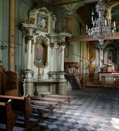 Zdjęcie nr 3: Drewniany kościół pw. św. Mikołaja w Polance jest budowlą orientowaną. Do prostokątnej nawy przylega węższe, wydłużone, trójbocznie zamknięte prezbiterium z piętrową zakrystią na osi o poligonalnym zamknięciu. Do zakrystii przylega od południa kruchta. Fragment północnej ściany prezbiterium jest murowany. Od zachodu do nawy dobudowano czworoboczną wieżę poprzedzoną przedsionkiem, który również dostawiono do nawy od południa. Prezbiterium i nawę wzniesiono na zrąb, natomiast wieżę w konstrukcji słupowej. Wieża na rzucie kwadratu posiada dwie kondygnacje. Dolna jest tej samej szerokości co nawa, górna natomiast znacznie węższa. Jej masyw podzielono smukłymi pilastrami i lizenami, zaś poniżej profilowanego gzymsu koronującego umieszczono wyrzynaną w desce koronkę. Kondygnacje oddzielono daszkiem gontowym zlewającym się po bokach z dachem kościoła. Wieżę nakryto kopulastym hełmem blaszanym, zwieńczonym blaszanym obeliskiem z krzyżem. Prezbiterium i nawę nakryto eternitowym dachem siodłowym podkreślonym profilowanym gzymsem. Nad nawą w części wschodniej zainstalowano wieżyczkę na sygnaturkę w formie wielobocznego graniastosłupa przykrytego cebulastą banią z krzyżem. Dokoła kościoła założono daszek gontowy chroniący podwaliny. Pod kościołem urządzono kryptę grzebalną. Wnętrze kościoła artykułowano za pomocą pilastrów i gzymsu. Całość nakryto stropem z fasetą. Otwór tęczowy uzyskał kształt trójlistnego, ściętego łuku, wspartego na filarkach ustawionych na profilowanej belce zawieszonej na kroksztynach. W części zachodniej nawy urządzono chór muzyczny, wsparty na dwóch kolumnach jońskich z przedpiersiem rozczłonkowanym balasami. We wnętrzu ustawiono ołtarz główny i dwa ołtarze boczne oraz ambonę, a na chórze muzycznym zainstalowano prospekt organowy.