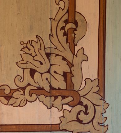 Zdjęcie nr 3: Polichromia malarska we wnętrzu drewnianego kościoła parafialnego w Polance Wielkiej zachowała się w prezbiterium, nawie oraz w przedsionku urządzonym w przyziemiu wieży. W prezbiterium i nawie zastosowano podział ramowy uwzględniający drewniane pilastry artykułujące ściany, gzyms oraz fasetę. Na ścianach pomiędzy pilastrami wprowadzono czworoboczne panneau o narożach utworzonych w stylizowanych formach nawiązujących do motywów roślinno-kwiatowych. Fasetę udekorowano rytmicznie rozłożonym ornamentem z motywów kwiatowych w formie dekoracyjnego fryzu, korespondującego z ornamentalną bordiurą poprowadzoną wzdłuż krawędzi płaskiego stropu. Na stropie w prezbiterium wyobrażono Trójcę Świętą, natomiast w nawie Matkę Boską Różańcową otoczoną przez tajemnice różańcowe w medalionach. Trójcę Świętą wyobrażono na obłokach na niebieskim tle usianym złotymi gwiazdkami. Frontalnie ujęty Bóg Ojciec został ukazany jako siwobrody starzec o bujnych siwych włosach. W prawej ręce trzyma złote berło, lewą zaś wyciąga przed siebie. Bóg Ojciec stopy wspiera o niebieski glob wyłaniający się z obłoków poniżej. Jego twarz charakteryzuje jasna karnacja, szeroko otwarte oczy, wydatny nos i usta. Głowę otacza długa, siwa broda i podobne włosy. Obok Boga Ojca z lewej strony siedzi Chrystus, który obie nogi wspiera na globie. Zbawiciel prawą ręką podtrzymuje oparty o ramię drewniany krzyż, lewą zaś ma odsuniętą od siebie. Jezus został przedstawiony w trzech czwartych w prawo. Jest to dojrzały mężczyzna o pociągłej twarzy okolonej brązowymi, długimi włosami spływającymi na ramiona oraz brodą. Ma jasną karnację, prosty nos i wydatne usta. Nagi tors okrywa bladoszkarłatny płaszcz odsłaniający prawą nogę. Na dłoniach i stopach widoczne są rany po gwoździach. Głowę Jezusa okala świetlisty nimb. Powyżej obu postaci na tle rozjaśnionego nieba unosi się gołębica Ducha Świętego w promienistym otoku. Polichromia stropu w nawie została zakomponowana w oparciu o zmniejszające się koncentryczne okręgi wpisane w dekoracjne panneau o narożach utworzonych ze stylizowanych form nawiązujących do motywów roślinno-kwiatowych. W środkowym okręgu ukazano zasiadającą na obłokach Matkę Boską z Dzieciątkiem otoczoną okrągłym obramieniem utworzonym z wielobarwnego ornamentu z motywem naprzemiennie ułożonych lancetowatych liści-łusek. Madonna została przedstawiona frontalnie, z prawą ręką przyłożoną do piersi, lewą zaś obejmuje Dzieciątko Jezus siedzące na globie ułożonym na kolanach matki podtrzymywanym przez anioła. Maryja ma pociągłą twarz o wydatnym nosie i wargach. Jej spojrzenie półprzymkniętych oczu skierowane jest pokornie ku dołowi. Głowę Marii otaczają, brązowe, falujące włosy spływające na ramiona. Madonna ubrana jest w czerwoną suknię przewiązaną złocistą szarfą w pasie i niebieski płaszcz lamowany złotą taśmą, spięty pod szyją z lewą połą osłaniającą jej kolana. Lewą stopę Matka Boska wspiera o wystający spod płaszcza poniżej złoty półksiężyc. Siedzące na globie Dzieciątko ujęte zostało w trzech czwartych w lewo. Mały Jezus prawą ręką nakłada matce złotą koronę, w lewej zaś trzyma lilię. Zbawiciel ma owalną twarz o jasnej karnacjim i rumianych policzkach z drobnym nosem i ustami. Jego głowę okalają jasne loki. Ubrany jest w jasną przepaskę przerzuconą przez prawe ramię oraz biodra. Głowy obu postaci otaczają świetliste promienie. Z prawej strony Marii stoi ujęty w trzech czwarty w prawo anioł, z twarzą zwróconą w stronę widza, podtrzymujący oburącz niebieski glob, na którym siedzi Jezus. Uskrzydlony anioł o jasnobrązowych włosach ubrany jest w zieloną tunikę przewiązaną w pasie. Za Madonną z lewej strony widoczny jest asystujący drugi anioł w cynobrowej tunice i jasnych włosach spływających na ramiona. Pod półksiężycem na tle obłoków widoczne są trzy uskrzydlone główki anielskie. Wokół Matki Boskiej rozmieszczono owalne medaliony z blachy miedzianej malowane w piętnaście tajemnic Różańca świętego. Ich narracja rozpoczyna się nad głową Madonny. Każda ze scen oparta jest o kilkuosobową kompozycję. Idąc w lewo namalowano: Zwiastowanie Marii, Nawiedzenie św. Elżbiety, Boże Narodzenie, Ofiarowanie w świątyni, Znalezienie w świątyni, Modlitwa w Ogrójcu, Biczowanie, Cierniem ukoronowanie, Niesienie krzyża, Ukrzyżowanie, Zmartwychwstanie, Wniebowstąpienie, Zesłanie Ducha Świętego, Wniebowzięcie Marii, Ukoronowanie Marii w niebie. Pomiędzy medalionami namalowano czerwone róże. Całoś obramienia ornamentalny okrąg. Dekorację w przedsionku utworzono za pomocą iluzjonistycznie malowanych cynobrowych kolumn o korynckich kapitelach ustawionych na wysokich postumentach, podtrzymujących belkowanie. Pomiędzy kolumnami ściany są gładkie, bladoniebieskie. Strop ozdobiono obramieniem w formie czworobocznego panneau o narożach utworzonych ze stylizowanych form nawiązujących do motywów roślinno-kwiatowych. 