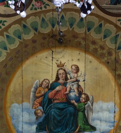 Zdjęcie nr 1: Polichromia malarska we wnętrzu drewnianego kościoła parafialnego w Polance Wielkiej zachowała się w prezbiterium, nawie oraz w przedsionku urządzonym w przyziemiu wieży. W prezbiterium i nawie zastosowano podział ramowy uwzględniający drewniane pilastry artykułujące ściany, gzyms oraz fasetę. Na ścianach pomiędzy pilastrami wprowadzono czworoboczne panneau o narożach utworzonych w stylizowanych formach nawiązujących do motywów roślinno-kwiatowych. Fasetę udekorowano rytmicznie rozłożonym ornamentem z motywów kwiatowych w formie dekoracyjnego fryzu, korespondującego z ornamentalną bordiurą poprowadzoną wzdłuż krawędzi płaskiego stropu. Na stropie w prezbiterium wyobrażono Trójcę Świętą, natomiast w nawie Matkę Boską Różańcową otoczoną przez tajemnice różańcowe w medalionach. Trójcę Świętą wyobrażono na obłokach na niebieskim tle usianym złotymi gwiazdkami. Frontalnie ujęty Bóg Ojciec został ukazany jako siwobrody starzec o bujnych siwych włosach. W prawej ręce trzyma złote berło, lewą zaś wyciąga przed siebie. Bóg Ojciec stopy wspiera o niebieski glob wyłaniający się z obłoków poniżej. Jego twarz charakteryzuje jasna karnacja, szeroko otwarte oczy, wydatny nos i usta. Głowę otacza długa, siwa broda i podobne włosy. Obok Boga Ojca z lewej strony siedzi Chrystus, który obie nogi wspiera na globie. Zbawiciel prawą ręką podtrzymuje oparty o ramię drewniany krzyż, lewą zaś ma odsuniętą od siebie. Jezus został przedstawiony w trzech czwartych w prawo. Jest to dojrzały mężczyzna o pociągłej twarzy okolonej brązowymi, długimi włosami spływającymi na ramiona oraz brodą. Ma jasną karnację, prosty nos i wydatne usta. Nagi tors okrywa bladoszkarłatny płaszcz odsłaniający prawą nogę. Na dłoniach i stopach widoczne są rany po gwoździach. Głowę Jezusa okala świetlisty nimb. Powyżej obu postaci na tle rozjaśnionego nieba unosi się gołębica Ducha Świętego w promienistym otoku. Polichromia stropu w nawie została zakomponowana w oparciu o zmniejszające się koncentryczne okręgi wpisane w dekoracjne panneau o narożach utworzonych ze stylizowanych form nawiązujących do motywów roślinno-kwiatowych. W środkowym okręgu ukazano zasiadającą na obłokach Matkę Boską z Dzieciątkiem otoczoną okrągłym obramieniem utworzonym z wielobarwnego ornamentu z motywem naprzemiennie ułożonych lancetowatych liści-łusek. Madonna została przedstawiona frontalnie, z prawą ręką przyłożoną do piersi, lewą zaś obejmuje Dzieciątko Jezus siedzące na globie ułożonym na kolanach matki podtrzymywanym przez anioła. Maryja ma pociągłą twarz o wydatnym nosie i wargach. Jej spojrzenie półprzymkniętych oczu skierowane jest pokornie ku dołowi. Głowę Marii otaczają, brązowe, falujące włosy spływające na ramiona. Madonna ubrana jest w czerwoną suknię przewiązaną złocistą szarfą w pasie i niebieski płaszcz lamowany złotą taśmą, spięty pod szyją z lewą połą osłaniającą jej kolana. Lewą stopę Matka Boska wspiera o wystający spod płaszcza poniżej złoty półksiężyc. Siedzące na globie Dzieciątko ujęte zostało w trzech czwartych w lewo. Mały Jezus prawą ręką nakłada matce złotą koronę, w lewej zaś trzyma lilię. Zbawiciel ma owalną twarz o jasnej karnacjim i rumianych policzkach z drobnym nosem i ustami. Jego głowę okalają jasne loki. Ubrany jest w jasną przepaskę przerzuconą przez prawe ramię oraz biodra. Głowy obu postaci otaczają świetliste promienie. Z prawej strony Marii stoi ujęty w trzech czwarty w prawo anioł, z twarzą zwróconą w stronę widza, podtrzymujący oburącz niebieski glob, na którym siedzi Jezus. Uskrzydlony anioł o jasnobrązowych włosach ubrany jest w zieloną tunikę przewiązaną w pasie. Za Madonną z lewej strony widoczny jest asystujący drugi anioł w cynobrowej tunice i jasnych włosach spływających na ramiona. Pod półksiężycem na tle obłoków widoczne są trzy uskrzydlone główki anielskie. Wokół Matki Boskiej rozmieszczono owalne medaliony z blachy miedzianej malowane w piętnaście tajemnic Różańca świętego. Ich narracja rozpoczyna się nad głową Madonny. Każda ze scen oparta jest o kilkuosobową kompozycję. Idąc w lewo namalowano: Zwiastowanie Marii, Nawiedzenie św. Elżbiety, Boże Narodzenie, Ofiarowanie w świątyni, Znalezienie w świątyni, Modlitwa w Ogrójcu, Biczowanie, Cierniem ukoronowanie, Niesienie krzyża, Ukrzyżowanie, Zmartwychwstanie, Wniebowstąpienie, Zesłanie Ducha Świętego, Wniebowzięcie Marii, Ukoronowanie Marii w niebie. Pomiędzy medalionami namalowano czerwone róże. Całoś obramienia ornamentalny okrąg. Dekorację w przedsionku utworzono za pomocą iluzjonistycznie malowanych cynobrowych kolumn o korynckich kapitelach ustawionych na wysokich postumentach, podtrzymujących belkowanie. Pomiędzy kolumnami ściany są gładkie, bladoniebieskie. Strop ozdobiono obramieniem w formie czworobocznego panneau o narożach utworzonych ze stylizowanych form nawiązujących do motywów roślinno-kwiatowych. 