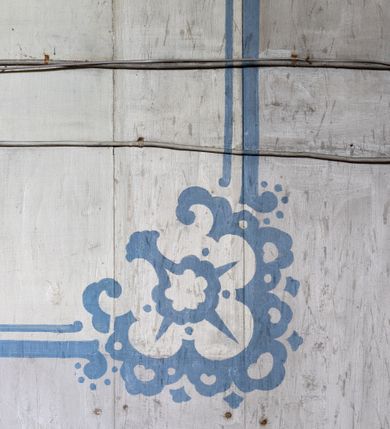 Zdjęcie nr 14: Polichromia malarska we wnętrzu drewnianego kościoła parafialnego w Polance Wielkiej zachowała się w prezbiterium, nawie oraz w przedsionku urządzonym w przyziemiu wieży. W prezbiterium i nawie zastosowano podział ramowy uwzględniający drewniane pilastry artykułujące ściany, gzyms oraz fasetę. Na ścianach pomiędzy pilastrami wprowadzono czworoboczne panneau o narożach utworzonych w stylizowanych formach nawiązujących do motywów roślinno-kwiatowych. Fasetę udekorowano rytmicznie rozłożonym ornamentem z motywów kwiatowych w formie dekoracyjnego fryzu, korespondującego z ornamentalną bordiurą poprowadzoną wzdłuż krawędzi płaskiego stropu. Na stropie w prezbiterium wyobrażono Trójcę Świętą, natomiast w nawie Matkę Boską Różańcową otoczoną przez tajemnice różańcowe w medalionach. Trójcę Świętą wyobrażono na obłokach na niebieskim tle usianym złotymi gwiazdkami. Frontalnie ujęty Bóg Ojciec został ukazany jako siwobrody starzec o bujnych siwych włosach. W prawej ręce trzyma złote berło, lewą zaś wyciąga przed siebie. Bóg Ojciec stopy wspiera o niebieski glob wyłaniający się z obłoków poniżej. Jego twarz charakteryzuje jasna karnacja, szeroko otwarte oczy, wydatny nos i usta. Głowę otacza długa, siwa broda i podobne włosy. Obok Boga Ojca z lewej strony siedzi Chrystus, który obie nogi wspiera na globie. Zbawiciel prawą ręką podtrzymuje oparty o ramię drewniany krzyż, lewą zaś ma odsuniętą od siebie. Jezus został przedstawiony w trzech czwartych w prawo. Jest to dojrzały mężczyzna o pociągłej twarzy okolonej brązowymi, długimi włosami spływającymi na ramiona oraz brodą. Ma jasną karnację, prosty nos i wydatne usta. Nagi tors okrywa bladoszkarłatny płaszcz odsłaniający prawą nogę. Na dłoniach i stopach widoczne są rany po gwoździach. Głowę Jezusa okala świetlisty nimb. Powyżej obu postaci na tle rozjaśnionego nieba unosi się gołębica Ducha Świętego w promienistym otoku. Polichromia stropu w nawie została zakomponowana w oparciu o zmniejszające się koncentryczne okręgi wpisane w dekoracjne panneau o narożach utworzonych ze stylizowanych form nawiązujących do motywów roślinno-kwiatowych. W środkowym okręgu ukazano zasiadającą na obłokach Matkę Boską z Dzieciątkiem otoczoną okrągłym obramieniem utworzonym z wielobarwnego ornamentu z motywem naprzemiennie ułożonych lancetowatych liści-łusek. Madonna została przedstawiona frontalnie, z prawą ręką przyłożoną do piersi, lewą zaś obejmuje Dzieciątko Jezus siedzące na globie ułożonym na kolanach matki podtrzymywanym przez anioła. Maryja ma pociągłą twarz o wydatnym nosie i wargach. Jej spojrzenie półprzymkniętych oczu skierowane jest pokornie ku dołowi. Głowę Marii otaczają, brązowe, falujące włosy spływające na ramiona. Madonna ubrana jest w czerwoną suknię przewiązaną złocistą szarfą w pasie i niebieski płaszcz lamowany złotą taśmą, spięty pod szyją z lewą połą osłaniającą jej kolana. Lewą stopę Matka Boska wspiera o wystający spod płaszcza poniżej złoty półksiężyc. Siedzące na globie Dzieciątko ujęte zostało w trzech czwartych w lewo. Mały Jezus prawą ręką nakłada matce złotą koronę, w lewej zaś trzyma lilię. Zbawiciel ma owalną twarz o jasnej karnacjim i rumianych policzkach z drobnym nosem i ustami. Jego głowę okalają jasne loki. Ubrany jest w jasną przepaskę przerzuconą przez prawe ramię oraz biodra. Głowy obu postaci otaczają świetliste promienie. Z prawej strony Marii stoi ujęty w trzech czwarty w prawo anioł, z twarzą zwróconą w stronę widza, podtrzymujący oburącz niebieski glob, na którym siedzi Jezus. Uskrzydlony anioł o jasnobrązowych włosach ubrany jest w zieloną tunikę przewiązaną w pasie. Za Madonną z lewej strony widoczny jest asystujący drugi anioł w cynobrowej tunice i jasnych włosach spływających na ramiona. Pod półksiężycem na tle obłoków widoczne są trzy uskrzydlone główki anielskie. Wokół Matki Boskiej rozmieszczono owalne medaliony z blachy miedzianej malowane w piętnaście tajemnic Różańca świętego. Ich narracja rozpoczyna się nad głową Madonny. Każda ze scen oparta jest o kilkuosobową kompozycję. Idąc w lewo namalowano: Zwiastowanie Marii, Nawiedzenie św. Elżbiety, Boże Narodzenie, Ofiarowanie w świątyni, Znalezienie w świątyni, Modlitwa w Ogrójcu, Biczowanie, Cierniem ukoronowanie, Niesienie krzyża, Ukrzyżowanie, Zmartwychwstanie, Wniebowstąpienie, Zesłanie Ducha Świętego, Wniebowzięcie Marii, Ukoronowanie Marii w niebie. Pomiędzy medalionami namalowano czerwone róże. Całoś obramienia ornamentalny okrąg. Dekorację w przedsionku utworzono za pomocą iluzjonistycznie malowanych cynobrowych kolumn o korynckich kapitelach ustawionych na wysokich postumentach, podtrzymujących belkowanie. Pomiędzy kolumnami ściany są gładkie, bladoniebieskie. Strop ozdobiono obramieniem w formie czworobocznego panneau o narożach utworzonych ze stylizowanych form nawiązujących do motywów roślinno-kwiatowych. 