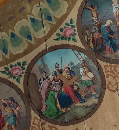 Zdjęcie nr 10: Polichromia malarska we wnętrzu drewnianego kościoła parafialnego w Polance Wielkiej zachowała się w prezbiterium, nawie oraz w przedsionku urządzonym w przyziemiu wieży. W prezbiterium i nawie zastosowano podział ramowy uwzględniający drewniane pilastry artykułujące ściany, gzyms oraz fasetę. Na ścianach pomiędzy pilastrami wprowadzono czworoboczne panneau o narożach utworzonych w stylizowanych formach nawiązujących do motywów roślinno-kwiatowych. Fasetę udekorowano rytmicznie rozłożonym ornamentem z motywów kwiatowych w formie dekoracyjnego fryzu, korespondującego z ornamentalną bordiurą poprowadzoną wzdłuż krawędzi płaskiego stropu. Na stropie w prezbiterium wyobrażono Trójcę Świętą, natomiast w nawie Matkę Boską Różańcową otoczoną przez tajemnice różańcowe w medalionach. Trójcę Świętą wyobrażono na obłokach na niebieskim tle usianym złotymi gwiazdkami. Frontalnie ujęty Bóg Ojciec został ukazany jako siwobrody starzec o bujnych siwych włosach. W prawej ręce trzyma złote berło, lewą zaś wyciąga przed siebie. Bóg Ojciec stopy wspiera o niebieski glob wyłaniający się z obłoków poniżej. Jego twarz charakteryzuje jasna karnacja, szeroko otwarte oczy, wydatny nos i usta. Głowę otacza długa, siwa broda i podobne włosy. Obok Boga Ojca z lewej strony siedzi Chrystus, który obie nogi wspiera na globie. Zbawiciel prawą ręką podtrzymuje oparty o ramię drewniany krzyż, lewą zaś ma odsuniętą od siebie. Jezus został przedstawiony w trzech czwartych w prawo. Jest to dojrzały mężczyzna o pociągłej twarzy okolonej brązowymi, długimi włosami spływającymi na ramiona oraz brodą. Ma jasną karnację, prosty nos i wydatne usta. Nagi tors okrywa bladoszkarłatny płaszcz odsłaniający prawą nogę. Na dłoniach i stopach widoczne są rany po gwoździach. Głowę Jezusa okala świetlisty nimb. Powyżej obu postaci na tle rozjaśnionego nieba unosi się gołębica Ducha Świętego w promienistym otoku. Polichromia stropu w nawie została zakomponowana w oparciu o zmniejszające się koncentryczne okręgi wpisane w dekoracjne panneau o narożach utworzonych ze stylizowanych form nawiązujących do motywów roślinno-kwiatowych. W środkowym okręgu ukazano zasiadającą na obłokach Matkę Boską z Dzieciątkiem otoczoną okrągłym obramieniem utworzonym z wielobarwnego ornamentu z motywem naprzemiennie ułożonych lancetowatych liści-łusek. Madonna została przedstawiona frontalnie, z prawą ręką przyłożoną do piersi, lewą zaś obejmuje Dzieciątko Jezus siedzące na globie ułożonym na kolanach matki podtrzymywanym przez anioła. Maryja ma pociągłą twarz o wydatnym nosie i wargach. Jej spojrzenie półprzymkniętych oczu skierowane jest pokornie ku dołowi. Głowę Marii otaczają, brązowe, falujące włosy spływające na ramiona. Madonna ubrana jest w czerwoną suknię przewiązaną złocistą szarfą w pasie i niebieski płaszcz lamowany złotą taśmą, spięty pod szyją z lewą połą osłaniającą jej kolana. Lewą stopę Matka Boska wspiera o wystający spod płaszcza poniżej złoty półksiężyc. Siedzące na globie Dzieciątko ujęte zostało w trzech czwartych w lewo. Mały Jezus prawą ręką nakłada matce złotą koronę, w lewej zaś trzyma lilię. Zbawiciel ma owalną twarz o jasnej karnacjim i rumianych policzkach z drobnym nosem i ustami. Jego głowę okalają jasne loki. Ubrany jest w jasną przepaskę przerzuconą przez prawe ramię oraz biodra. Głowy obu postaci otaczają świetliste promienie. Z prawej strony Marii stoi ujęty w trzech czwarty w prawo anioł, z twarzą zwróconą w stronę widza, podtrzymujący oburącz niebieski glob, na którym siedzi Jezus. Uskrzydlony anioł o jasnobrązowych włosach ubrany jest w zieloną tunikę przewiązaną w pasie. Za Madonną z lewej strony widoczny jest asystujący drugi anioł w cynobrowej tunice i jasnych włosach spływających na ramiona. Pod półksiężycem na tle obłoków widoczne są trzy uskrzydlone główki anielskie. Wokół Matki Boskiej rozmieszczono owalne medaliony z blachy miedzianej malowane w piętnaście tajemnic Różańca świętego. Ich narracja rozpoczyna się nad głową Madonny. Każda ze scen oparta jest o kilkuosobową kompozycję. Idąc w lewo namalowano: Zwiastowanie Marii, Nawiedzenie św. Elżbiety, Boże Narodzenie, Ofiarowanie w świątyni, Znalezienie w świątyni, Modlitwa w Ogrójcu, Biczowanie, Cierniem ukoronowanie, Niesienie krzyża, Ukrzyżowanie, Zmartwychwstanie, Wniebowstąpienie, Zesłanie Ducha Świętego, Wniebowzięcie Marii, Ukoronowanie Marii w niebie. Pomiędzy medalionami namalowano czerwone róże. Całoś obramienia ornamentalny okrąg. Dekorację w przedsionku utworzono za pomocą iluzjonistycznie malowanych cynobrowych kolumn o korynckich kapitelach ustawionych na wysokich postumentach, podtrzymujących belkowanie. Pomiędzy kolumnami ściany są gładkie, bladoniebieskie. Strop ozdobiono obramieniem w formie czworobocznego panneau o narożach utworzonych ze stylizowanych form nawiązujących do motywów roślinno-kwiatowych. 
