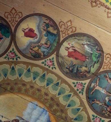 Zdjęcie nr 12: Polichromia malarska we wnętrzu drewnianego kościoła parafialnego w Polance Wielkiej zachowała się w prezbiterium, nawie oraz w przedsionku urządzonym w przyziemiu wieży. W prezbiterium i nawie zastosowano podział ramowy uwzględniający drewniane pilastry artykułujące ściany, gzyms oraz fasetę. Na ścianach pomiędzy pilastrami wprowadzono czworoboczne panneau o narożach utworzonych w stylizowanych formach nawiązujących do motywów roślinno-kwiatowych. Fasetę udekorowano rytmicznie rozłożonym ornamentem z motywów kwiatowych w formie dekoracyjnego fryzu, korespondującego z ornamentalną bordiurą poprowadzoną wzdłuż krawędzi płaskiego stropu. Na stropie w prezbiterium wyobrażono Trójcę Świętą, natomiast w nawie Matkę Boską Różańcową otoczoną przez tajemnice różańcowe w medalionach. Trójcę Świętą wyobrażono na obłokach na niebieskim tle usianym złotymi gwiazdkami. Frontalnie ujęty Bóg Ojciec został ukazany jako siwobrody starzec o bujnych siwych włosach. W prawej ręce trzyma złote berło, lewą zaś wyciąga przed siebie. Bóg Ojciec stopy wspiera o niebieski glob wyłaniający się z obłoków poniżej. Jego twarz charakteryzuje jasna karnacja, szeroko otwarte oczy, wydatny nos i usta. Głowę otacza długa, siwa broda i podobne włosy. Obok Boga Ojca z lewej strony siedzi Chrystus, który obie nogi wspiera na globie. Zbawiciel prawą ręką podtrzymuje oparty o ramię drewniany krzyż, lewą zaś ma odsuniętą od siebie. Jezus został przedstawiony w trzech czwartych w prawo. Jest to dojrzały mężczyzna o pociągłej twarzy okolonej brązowymi, długimi włosami spływającymi na ramiona oraz brodą. Ma jasną karnację, prosty nos i wydatne usta. Nagi tors okrywa bladoszkarłatny płaszcz odsłaniający prawą nogę. Na dłoniach i stopach widoczne są rany po gwoździach. Głowę Jezusa okala świetlisty nimb. Powyżej obu postaci na tle rozjaśnionego nieba unosi się gołębica Ducha Świętego w promienistym otoku. Polichromia stropu w nawie została zakomponowana w oparciu o zmniejszające się koncentryczne okręgi wpisane w dekoracjne panneau o narożach utworzonych ze stylizowanych form nawiązujących do motywów roślinno-kwiatowych. W środkowym okręgu ukazano zasiadającą na obłokach Matkę Boską z Dzieciątkiem otoczoną okrągłym obramieniem utworzonym z wielobarwnego ornamentu z motywem naprzemiennie ułożonych lancetowatych liści-łusek. Madonna została przedstawiona frontalnie, z prawą ręką przyłożoną do piersi, lewą zaś obejmuje Dzieciątko Jezus siedzące na globie ułożonym na kolanach matki podtrzymywanym przez anioła. Maryja ma pociągłą twarz o wydatnym nosie i wargach. Jej spojrzenie półprzymkniętych oczu skierowane jest pokornie ku dołowi. Głowę Marii otaczają, brązowe, falujące włosy spływające na ramiona. Madonna ubrana jest w czerwoną suknię przewiązaną złocistą szarfą w pasie i niebieski płaszcz lamowany złotą taśmą, spięty pod szyją z lewą połą osłaniającą jej kolana. Lewą stopę Matka Boska wspiera o wystający spod płaszcza poniżej złoty półksiężyc. Siedzące na globie Dzieciątko ujęte zostało w trzech czwartych w lewo. Mały Jezus prawą ręką nakłada matce złotą koronę, w lewej zaś trzyma lilię. Zbawiciel ma owalną twarz o jasnej karnacjim i rumianych policzkach z drobnym nosem i ustami. Jego głowę okalają jasne loki. Ubrany jest w jasną przepaskę przerzuconą przez prawe ramię oraz biodra. Głowy obu postaci otaczają świetliste promienie. Z prawej strony Marii stoi ujęty w trzech czwarty w prawo anioł, z twarzą zwróconą w stronę widza, podtrzymujący oburącz niebieski glob, na którym siedzi Jezus. Uskrzydlony anioł o jasnobrązowych włosach ubrany jest w zieloną tunikę przewiązaną w pasie. Za Madonną z lewej strony widoczny jest asystujący drugi anioł w cynobrowej tunice i jasnych włosach spływających na ramiona. Pod półksiężycem na tle obłoków widoczne są trzy uskrzydlone główki anielskie. Wokół Matki Boskiej rozmieszczono owalne medaliony z blachy miedzianej malowane w piętnaście tajemnic Różańca świętego. Ich narracja rozpoczyna się nad głową Madonny. Każda ze scen oparta jest o kilkuosobową kompozycję. Idąc w lewo namalowano: Zwiastowanie Marii, Nawiedzenie św. Elżbiety, Boże Narodzenie, Ofiarowanie w świątyni, Znalezienie w świątyni, Modlitwa w Ogrójcu, Biczowanie, Cierniem ukoronowanie, Niesienie krzyża, Ukrzyżowanie, Zmartwychwstanie, Wniebowstąpienie, Zesłanie Ducha Świętego, Wniebowzięcie Marii, Ukoronowanie Marii w niebie. Pomiędzy medalionami namalowano czerwone róże. Całoś obramienia ornamentalny okrąg. Dekorację w przedsionku utworzono za pomocą iluzjonistycznie malowanych cynobrowych kolumn o korynckich kapitelach ustawionych na wysokich postumentach, podtrzymujących belkowanie. Pomiędzy kolumnami ściany są gładkie, bladoniebieskie. Strop ozdobiono obramieniem w formie czworobocznego panneau o narożach utworzonych ze stylizowanych form nawiązujących do motywów roślinno-kwiatowych. 