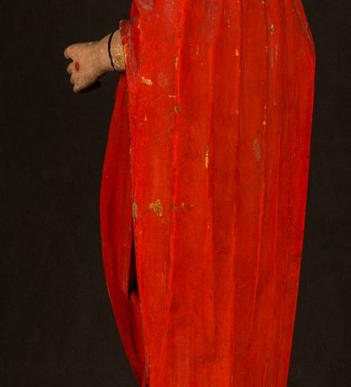 Zdjęcie nr 18: Rzeźba pełnoplastyczna, z tyłu opracowana. Chrystus, ukazany w całej postaci, frontalnie, stoi i na niewysokiej wypukłej podstawie, w kontrapoście, z prawą nogą ugiętą w kolanie. Ręce ugięte w łokciach, prawą błogosławi, lewą podtrzymuje połę płaszcza i zapewne niezachowane drzewce chorągwi. Głowa wydłużona, z wysokim czołem okolona krótkim zarostem i długimi ciemnymi włosami spływającymi w puklach na barki i plecy. Twarz pociągła, z wąskim nosem i małymi ustami. Ciało nagie, o jasnej karnacji, z ranami na dłoniach, stopach i w prawym boku, okryte perizonium oraz długim, sięgającym do ziemi, czerwonym płaszczem z niebieską podszewką, narzuconym na ramiona, spiętym pod szyją i z prawą połą przerzuconą przez przód postaci; pod prawą ręką okazały fałd muszlowy. 