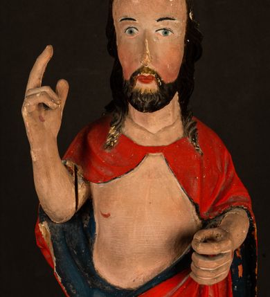 Zdjęcie nr 6: Rzeźba pełnoplastyczna, z tyłu opracowana. Chrystus, ukazany w całej postaci, frontalnie, stoi i na niewysokiej wypukłej podstawie, w kontrapoście, z prawą nogą ugiętą w kolanie. Ręce ugięte w łokciach, prawą błogosławi, lewą podtrzymuje połę płaszcza i zapewne niezachowane drzewce chorągwi. Głowa wydłużona, z wysokim czołem okolona krótkim zarostem i długimi ciemnymi włosami spływającymi w puklach na barki i plecy. Twarz pociągła, z wąskim nosem i małymi ustami. Ciało nagie, o jasnej karnacji, z ranami na dłoniach, stopach i w prawym boku, okryte perizonium oraz długim, sięgającym do ziemi, czerwonym płaszczem z niebieską podszewką, narzuconym na ramiona, spiętym pod szyją i z prawą połą przerzuconą przez przód postaci; pod prawą ręką okazały fałd muszlowy. 