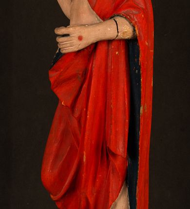 Zdjęcie nr 13: Rzeźba pełnoplastyczna, z tyłu opracowana. Chrystus, ukazany w całej postaci, frontalnie, stoi i na niewysokiej wypukłej podstawie, w kontrapoście, z prawą nogą ugiętą w kolanie. Ręce ugięte w łokciach, prawą błogosławi, lewą podtrzymuje połę płaszcza i zapewne niezachowane drzewce chorągwi. Głowa wydłużona, z wysokim czołem okolona krótkim zarostem i długimi ciemnymi włosami spływającymi w puklach na barki i plecy. Twarz pociągła, z wąskim nosem i małymi ustami. Ciało nagie, o jasnej karnacji, z ranami na dłoniach, stopach i w prawym boku, okryte perizonium oraz długim, sięgającym do ziemi, czerwonym płaszczem z niebieską podszewką, narzuconym na ramiona, spiętym pod szyją i z prawą połą przerzuconą przez przód postaci; pod prawą ręką okazały fałd muszlowy. 