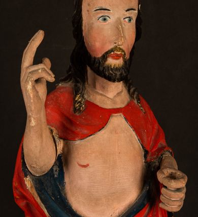Zdjęcie nr 8: Rzeźba pełnoplastyczna, z tyłu opracowana. Chrystus, ukazany w całej postaci, frontalnie, stoi i na niewysokiej wypukłej podstawie, w kontrapoście, z prawą nogą ugiętą w kolanie. Ręce ugięte w łokciach, prawą błogosławi, lewą podtrzymuje połę płaszcza i zapewne niezachowane drzewce chorągwi. Głowa wydłużona, z wysokim czołem okolona krótkim zarostem i długimi ciemnymi włosami spływającymi w puklach na barki i plecy. Twarz pociągła, z wąskim nosem i małymi ustami. Ciało nagie, o jasnej karnacji, z ranami na dłoniach, stopach i w prawym boku, okryte perizonium oraz długim, sięgającym do ziemi, czerwonym płaszczem z niebieską podszewką, narzuconym na ramiona, spiętym pod szyją i z prawą połą przerzuconą przez przód postaci; pod prawą ręką okazały fałd muszlowy. 