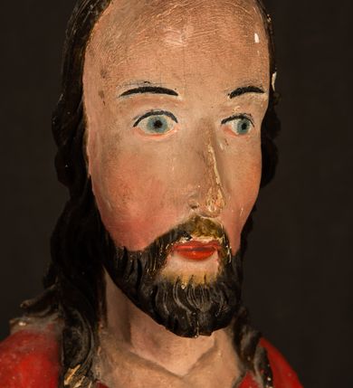 Zdjęcie nr 10: Rzeźba pełnoplastyczna, z tyłu opracowana. Chrystus, ukazany w całej postaci, frontalnie, stoi i na niewysokiej wypukłej podstawie, w kontrapoście, z prawą nogą ugiętą w kolanie. Ręce ugięte w łokciach, prawą błogosławi, lewą podtrzymuje połę płaszcza i zapewne niezachowane drzewce chorągwi. Głowa wydłużona, z wysokim czołem okolona krótkim zarostem i długimi ciemnymi włosami spływającymi w puklach na barki i plecy. Twarz pociągła, z wąskim nosem i małymi ustami. Ciało nagie, o jasnej karnacji, z ranami na dłoniach, stopach i w prawym boku, okryte perizonium oraz długim, sięgającym do ziemi, czerwonym płaszczem z niebieską podszewką, narzuconym na ramiona, spiętym pod szyją i z prawą połą przerzuconą przez przód postaci; pod prawą ręką okazały fałd muszlowy. 