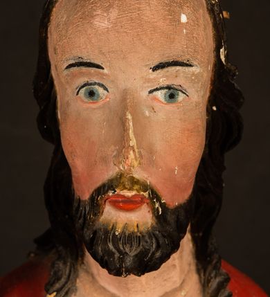 Zdjęcie nr 9: Rzeźba pełnoplastyczna, z tyłu opracowana. Chrystus, ukazany w całej postaci, frontalnie, stoi i na niewysokiej wypukłej podstawie, w kontrapoście, z prawą nogą ugiętą w kolanie. Ręce ugięte w łokciach, prawą błogosławi, lewą podtrzymuje połę płaszcza i zapewne niezachowane drzewce chorągwi. Głowa wydłużona, z wysokim czołem okolona krótkim zarostem i długimi ciemnymi włosami spływającymi w puklach na barki i plecy. Twarz pociągła, z wąskim nosem i małymi ustami. Ciało nagie, o jasnej karnacji, z ranami na dłoniach, stopach i w prawym boku, okryte perizonium oraz długim, sięgającym do ziemi, czerwonym płaszczem z niebieską podszewką, narzuconym na ramiona, spiętym pod szyją i z prawą połą przerzuconą przez przód postaci; pod prawą ręką okazały fałd muszlowy. 