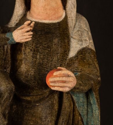 Zdjęcie nr 10: Stojąca figura Matki Boskiej z Dzieciątkiem reprezentuje przykład przyściennej rzeźby z tyłu wydrążonej. Maria stoi w lekkim kontrapoście, podkreślonym wysunięciem do przodu lewego kolana na niewielkim wzgórku. Prawą ręką podtrzymuje Dzieciątko, w lewej dłoni trzyma jabłko. Madonna ma mocno pociągłą twarz o jasnej karnacji z wysokim czołem, rumianych policzkach, długi, prosty nos i wydatne usta. Jej głowa osadzona jest na długiej szyi. Spod białej chusty ubranej na głowę i opadającej na ramiona widać brązowe włosy. Matka Boska na głowie ma koronę o ostrych, krótkich sterczynach. Nałożony na ciemnooliwkową suknię płaszcz w tym samym kolorze, podbity błękitem, tworzy dwa wałkowate zaokrąglone fałdy na brzuchu Marii, spływając miękkimi fałdami spod lewej ręki oraz festonem spod prawej ręki. Niżej fałdy płaszcza i sukni układają się niemal pionowo, opinając materią lewą nogę. Długa suknia odsłania czubki ciżemek. Dzieciątko zostało ujęte w trzech czwartych w prawo. Obie jego rączki wyciągnięte są przed siebie w stronę trzymanego przez Marię jabłka. Z kolei nóżki są skrzyżowane przy stopach. Jezus ma wyrazistą twarz o jasnej karnacji, małym nosem i wydatnych ustach. Jego głowę otaczają brązowe włosy układające się po bokach w charakterystyczne pukle. Jezus ubrany jest w długą, ciemnooliwkową tunikę odsłaniającą fragmenty stóp z charakterystycznymi mankietami przy rękawach. Szaty Matki Boskiej i Dzieciątka są srebrzone i laserowane.