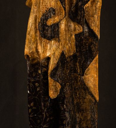 Zdjęcie nr 7: Rzeźba drążona ustawiona na niewielkim, wielobocznym postumencie. Maria ukazana w pozycji stojącej, frontalnie z ciałem ułożonym z lekkim kontrapoście. Lewą ręką podtrzymuje Dzieciątko Jezus, w prawej trzyma złocone berło zwieńczone kwiatem. Matka Boska przedstawiona jako młoda kobieta o podłużnej twarzy z wysokim czołem, migdałowatymi oczami oraz krótkim nosem i małymi ustami ułożonymi w delikatny uśmiech. Karnacja jasna, policzki wyraźnie zaróżowione. Długie, ciemne i falowane włosy rozdzielone przedziałkiem opadają na ramiona postaci. Na głowie Marii ciemna chusta oraz złocona korona (pozostałość korony?) lub diadem. Madonna jest ubrana w ciemną suknię z długimi rękawami dekorowaną motywem roślinnym oraz złocony płaszcz spięty pod szyją klamrą w kształcie kwiatu. Dzieciątko Jezus przedstawione w pozycji siedzącej z głową mocno pochyloną w bok i skrzyżowanymi stópkami. W ręku trzyma otwartą księgę. Twarz owalna, pulchna, ciemne oczy skierowane w lewo, usta w wyraźnym uśmiechu. Włosy, krótkie, falowane w kolorze brązowym. Dzieciątko jest ubrane w złoconą tkaninę udrapowaną wokół bioder. Figura polichromowana i częściowo złocona. Na odwrociu napis „Powtóre odzłocona / zarządem x(iędza) / Pawła Pomian Izdeb / skiego przez / Karol(a) Rośka / R(oku) P(ańskiego) 1853”.