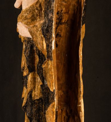 Zdjęcie nr 26: Rzeźba drążona ustawiona na niewielkim, wielobocznym postumencie. Maria ukazana w pozycji stojącej, frontalnie z ciałem ułożonym z lekkim kontrapoście. Lewą ręką podtrzymuje Dzieciątko Jezus, w prawej trzyma złocone berło zwieńczone kwiatem. Matka Boska przedstawiona jako młoda kobieta o podłużnej twarzy z wysokim czołem, migdałowatymi oczami oraz krótkim nosem i małymi ustami ułożonymi w delikatny uśmiech. Karnacja jasna, policzki wyraźnie zaróżowione. Długie, ciemne i falowane włosy rozdzielone przedziałkiem opadają na ramiona postaci. Na głowie Marii ciemna chusta oraz złocona korona (pozostałość korony?) lub diadem. Madonna jest ubrana w ciemną suknię z długimi rękawami dekorowaną motywem roślinnym oraz złocony płaszcz spięty pod szyją klamrą w kształcie kwiatu. Dzieciątko Jezus przedstawione w pozycji siedzącej z głową mocno pochyloną w bok i skrzyżowanymi stópkami. W ręku trzyma otwartą księgę. Twarz owalna, pulchna, ciemne oczy skierowane w lewo, usta w wyraźnym uśmiechu. Włosy, krótkie, falowane w kolorze brązowym. Dzieciątko jest ubrane w złoconą tkaninę udrapowaną wokół bioder. Figura polichromowana i częściowo złocona. Na odwrociu napis „Powtóre odzłocona / zarządem x(iędza) / Pawła Pomian Izdeb / skiego przez / Karol(a) Rośka / R(oku) P(ańskiego) 1853”.