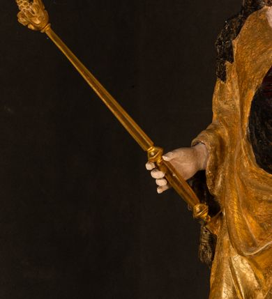 Zdjęcie nr 12: Rzeźba drążona ustawiona na niewielkim, wielobocznym postumencie. Maria ukazana w pozycji stojącej, frontalnie z ciałem ułożonym z lekkim kontrapoście. Lewą ręką podtrzymuje Dzieciątko Jezus, w prawej trzyma złocone berło zwieńczone kwiatem. Matka Boska przedstawiona jako młoda kobieta o podłużnej twarzy z wysokim czołem, migdałowatymi oczami oraz krótkim nosem i małymi ustami ułożonymi w delikatny uśmiech. Karnacja jasna, policzki wyraźnie zaróżowione. Długie, ciemne i falowane włosy rozdzielone przedziałkiem opadają na ramiona postaci. Na głowie Marii ciemna chusta oraz złocona korona (pozostałość korony?) lub diadem. Madonna jest ubrana w ciemną suknię z długimi rękawami dekorowaną motywem roślinnym oraz złocony płaszcz spięty pod szyją klamrą w kształcie kwiatu. Dzieciątko Jezus przedstawione w pozycji siedzącej z głową mocno pochyloną w bok i skrzyżowanymi stópkami. W ręku trzyma otwartą księgę. Twarz owalna, pulchna, ciemne oczy skierowane w lewo, usta w wyraźnym uśmiechu. Włosy, krótkie, falowane w kolorze brązowym. Dzieciątko jest ubrane w złoconą tkaninę udrapowaną wokół bioder. Figura polichromowana i częściowo złocona. Na odwrociu napis „Powtóre odzłocona / zarządem x(iędza) / Pawła Pomian Izdeb / skiego przez / Karol(a) Rośka / R(oku) P(ańskiego) 1853”.