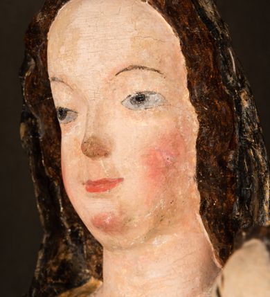 Zdjęcie nr 17: Rzeźba drążona ustawiona na niewielkim, wielobocznym postumencie. Maria ukazana w pozycji stojącej, frontalnie z ciałem ułożonym z lekkim kontrapoście. Lewą ręką podtrzymuje Dzieciątko Jezus, w prawej trzyma złocone berło zwieńczone kwiatem. Matka Boska przedstawiona jako młoda kobieta o podłużnej twarzy z wysokim czołem, migdałowatymi oczami oraz krótkim nosem i małymi ustami ułożonymi w delikatny uśmiech. Karnacja jasna, policzki wyraźnie zaróżowione. Długie, ciemne i falowane włosy rozdzielone przedziałkiem opadają na ramiona postaci. Na głowie Marii ciemna chusta oraz złocona korona (pozostałość korony?) lub diadem. Madonna jest ubrana w ciemną suknię z długimi rękawami dekorowaną motywem roślinnym oraz złocony płaszcz spięty pod szyją klamrą w kształcie kwiatu. Dzieciątko Jezus przedstawione w pozycji siedzącej z głową mocno pochyloną w bok i skrzyżowanymi stópkami. W ręku trzyma otwartą księgę. Twarz owalna, pulchna, ciemne oczy skierowane w lewo, usta w wyraźnym uśmiechu. Włosy, krótkie, falowane w kolorze brązowym. Dzieciątko jest ubrane w złoconą tkaninę udrapowaną wokół bioder. Figura polichromowana i częściowo złocona. Na odwrociu napis „Powtóre odzłocona / zarządem x(iędza) / Pawła Pomian Izdeb / skiego przez / Karol(a) Rośka / R(oku) P(ańskiego) 1853”.