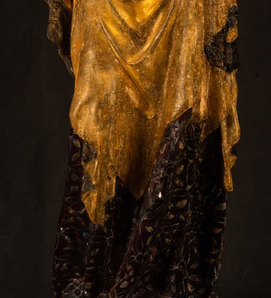 Zdjęcie nr 5: Rzeźba drążona ustawiona na niewielkim, wielobocznym postumencie. Maria ukazana w pozycji stojącej, frontalnie z ciałem ułożonym z lekkim kontrapoście. Lewą ręką podtrzymuje Dzieciątko Jezus, w prawej trzyma złocone berło zwieńczone kwiatem. Matka Boska przedstawiona jako młoda kobieta o podłużnej twarzy z wysokim czołem, migdałowatymi oczami oraz krótkim nosem i małymi ustami ułożonymi w delikatny uśmiech. Karnacja jasna, policzki wyraźnie zaróżowione. Długie, ciemne i falowane włosy rozdzielone przedziałkiem opadają na ramiona postaci. Na głowie Marii ciemna chusta oraz złocona korona (pozostałość korony?) lub diadem. Madonna jest ubrana w ciemną suknię z długimi rękawami dekorowaną motywem roślinnym oraz złocony płaszcz spięty pod szyją klamrą w kształcie kwiatu. Dzieciątko Jezus przedstawione w pozycji siedzącej z głową mocno pochyloną w bok i skrzyżowanymi stópkami. W ręku trzyma otwartą księgę. Twarz owalna, pulchna, ciemne oczy skierowane w lewo, usta w wyraźnym uśmiechu. Włosy, krótkie, falowane w kolorze brązowym. Dzieciątko jest ubrane w złoconą tkaninę udrapowaną wokół bioder. Figura polichromowana i częściowo złocona. Na odwrociu napis „Powtóre odzłocona / zarządem x(iędza) / Pawła Pomian Izdeb / skiego przez / Karol(a) Rośka / R(oku) P(ańskiego) 1853”.