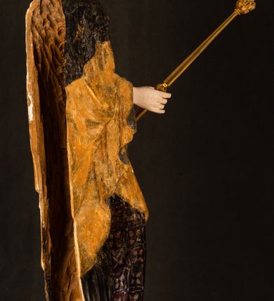 Zdjęcie nr 25: Rzeźba drążona ustawiona na niewielkim, wielobocznym postumencie. Maria ukazana w pozycji stojącej, frontalnie z ciałem ułożonym z lekkim kontrapoście. Lewą ręką podtrzymuje Dzieciątko Jezus, w prawej trzyma złocone berło zwieńczone kwiatem. Matka Boska przedstawiona jako młoda kobieta o podłużnej twarzy z wysokim czołem, migdałowatymi oczami oraz krótkim nosem i małymi ustami ułożonymi w delikatny uśmiech. Karnacja jasna, policzki wyraźnie zaróżowione. Długie, ciemne i falowane włosy rozdzielone przedziałkiem opadają na ramiona postaci. Na głowie Marii ciemna chusta oraz złocona korona (pozostałość korony?) lub diadem. Madonna jest ubrana w ciemną suknię z długimi rękawami dekorowaną motywem roślinnym oraz złocony płaszcz spięty pod szyją klamrą w kształcie kwiatu. Dzieciątko Jezus przedstawione w pozycji siedzącej z głową mocno pochyloną w bok i skrzyżowanymi stópkami. W ręku trzyma otwartą księgę. Twarz owalna, pulchna, ciemne oczy skierowane w lewo, usta w wyraźnym uśmiechu. Włosy, krótkie, falowane w kolorze brązowym. Dzieciątko jest ubrane w złoconą tkaninę udrapowaną wokół bioder. Figura polichromowana i częściowo złocona. Na odwrociu napis „Powtóre odzłocona / zarządem x(iędza) / Pawła Pomian Izdeb / skiego przez / Karol(a) Rośka / R(oku) P(ańskiego) 1853”.