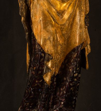 Zdjęcie nr 6: Rzeźba drążona ustawiona na niewielkim, wielobocznym postumencie. Maria ukazana w pozycji stojącej, frontalnie z ciałem ułożonym z lekkim kontrapoście. Lewą ręką podtrzymuje Dzieciątko Jezus, w prawej trzyma złocone berło zwieńczone kwiatem. Matka Boska przedstawiona jako młoda kobieta o podłużnej twarzy z wysokim czołem, migdałowatymi oczami oraz krótkim nosem i małymi ustami ułożonymi w delikatny uśmiech. Karnacja jasna, policzki wyraźnie zaróżowione. Długie, ciemne i falowane włosy rozdzielone przedziałkiem opadają na ramiona postaci. Na głowie Marii ciemna chusta oraz złocona korona (pozostałość korony?) lub diadem. Madonna jest ubrana w ciemną suknię z długimi rękawami dekorowaną motywem roślinnym oraz złocony płaszcz spięty pod szyją klamrą w kształcie kwiatu. Dzieciątko Jezus przedstawione w pozycji siedzącej z głową mocno pochyloną w bok i skrzyżowanymi stópkami. W ręku trzyma otwartą księgę. Twarz owalna, pulchna, ciemne oczy skierowane w lewo, usta w wyraźnym uśmiechu. Włosy, krótkie, falowane w kolorze brązowym. Dzieciątko jest ubrane w złoconą tkaninę udrapowaną wokół bioder. Figura polichromowana i częściowo złocona. Na odwrociu napis „Powtóre odzłocona / zarządem x(iędza) / Pawła Pomian Izdeb / skiego przez / Karol(a) Rośka / R(oku) P(ańskiego) 1853”.