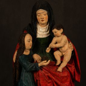 Zdjęcie nr 1: Rzeźba drążona przedstawiająca siedzącą św. Annę w towarzystwie klęczącej Marii oraz Dzieciątka Jezus. Anna ukazana frontalnie, z głową pochyloną nieznacznie w dół, obejmująca rękoma przedstawioną z prawej strony Marię oraz znajdujące się po lewej stronie Dzieciątko Jezus. Twarz świętej owalna o spokojnym wyrazie, z oczami skierowanymi w dół. Nos długi, prosty, na policzkach zaznaczony delikatny rumieniec. Anna ubrana jest w ciemnozieloną suknię przepasaną w talii, ciemnogranatową chustę zarzuconą na głowę, pod którą znajduje się biała podwika. Na ramiona i kolana postaci narzucony jest obszerny, czerwony płaszcz spod, którego widoczny jest ostro zakończony czubek brązowego buta św. Anny. Maria znajdująca się z lewej strony kompozycji została  przedstawiona jako młoda kobieta, klęcząca u stóp swojej matki i zwracająca się w kierunku siedzącego na kolanach Anny Dzieciątka Jezus. Owalną twarz Marii charakteryzuje wysokie czoło i cienkie, łukowato wygięte brwi. Długie, ciemne i lekko falowane włosy opadają na ramiona i plecy postaci. Maria swoją prawą rękę wspiera na kolanach Anny, lewą wyciąga przed siebie, podając Dzieciątku jabłko królewskie. Ubrana jest w ciemnogranatową suknię z długimi rękawami, spod której widoczne są bose stopy. Chrystus został ukazany jako nagi, ciemnowłosy chłopiec  o okrągłej twarzy z rumieńcem siedzący na kolanach św. Anny i wyciągający obie ręce w kierunku Marii. Rzeźba w pełni polichromowana.