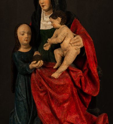 Zdjęcie nr 10: Rzeźba drążona przedstawiająca siedzącą św. Annę w towarzystwie klęczącej Marii oraz Dzieciątka Jezus. Anna ukazana frontalnie, z głową pochyloną nieznacznie w dół, obejmująca rękoma przedstawioną z prawej strony Marię oraz znajdujące się po lewej stronie Dzieciątko Jezus. Twarz świętej owalna o spokojnym wyrazie, z oczami skierowanymi w dół. Nos długi, prosty, na policzkach zaznaczony delikatny rumieniec. Anna ubrana jest w ciemnozieloną suknię przepasaną w talii, ciemnogranatową chustę zarzuconą na głowę, pod którą znajduje się biała podwika. Na ramiona i kolana postaci narzucony jest obszerny, czerwony płaszcz spod, którego widoczny jest ostro zakończony czubek brązowego buta św. Anny. Maria znajdująca się z lewej strony kompozycji została  przedstawiona jako młoda kobieta, klęcząca u stóp swojej matki i zwracająca się w kierunku siedzącego na kolanach Anny Dzieciątka Jezus. Owalną twarz Marii charakteryzuje wysokie czoło i cienkie, łukowato wygięte brwi. Długie, ciemne i lekko falowane włosy opadają na ramiona i plecy postaci. Maria swoją prawą rękę wspiera na kolanach Anny, lewą wyciąga przed siebie, podając Dzieciątku jabłko królewskie. Ubrana jest w ciemnogranatową suknię z długimi rękawami, spod której widoczne są bose stopy. Chrystus został ukazany jako nagi, ciemnowłosy chłopiec  o okrągłej twarzy z rumieńcem siedzący na kolanach św. Anny i wyciągający obie ręce w kierunku Marii. Rzeźba w pełni polichromowana.