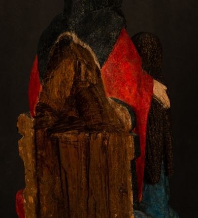 Zdjęcie nr 13: Rzeźba drążona przedstawiająca siedzącą św. Annę w towarzystwie klęczącej Marii oraz Dzieciątka Jezus. Anna ukazana frontalnie, z głową pochyloną nieznacznie w dół, obejmująca rękoma przedstawioną z prawej strony Marię oraz znajdujące się po lewej stronie Dzieciątko Jezus. Twarz świętej owalna o spokojnym wyrazie, z oczami skierowanymi w dół. Nos długi, prosty, na policzkach zaznaczony delikatny rumieniec. Anna ubrana jest w ciemnozieloną suknię przepasaną w talii, ciemnogranatową chustę zarzuconą na głowę, pod którą znajduje się biała podwika. Na ramiona i kolana postaci narzucony jest obszerny, czerwony płaszcz spod, którego widoczny jest ostro zakończony czubek brązowego buta św. Anny. Maria znajdująca się z lewej strony kompozycji została  przedstawiona jako młoda kobieta, klęcząca u stóp swojej matki i zwracająca się w kierunku siedzącego na kolanach Anny Dzieciątka Jezus. Owalną twarz Marii charakteryzuje wysokie czoło i cienkie, łukowato wygięte brwi. Długie, ciemne i lekko falowane włosy opadają na ramiona i plecy postaci. Maria swoją prawą rękę wspiera na kolanach Anny, lewą wyciąga przed siebie, podając Dzieciątku jabłko królewskie. Ubrana jest w ciemnogranatową suknię z długimi rękawami, spod której widoczne są bose stopy. Chrystus został ukazany jako nagi, ciemnowłosy chłopiec  o okrągłej twarzy z rumieńcem siedzący na kolanach św. Anny i wyciągający obie ręce w kierunku Marii. Rzeźba w pełni polichromowana.