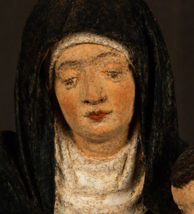 Zdjęcie nr 6: Rzeźba drążona przedstawiająca siedzącą św. Annę w towarzystwie klęczącej Marii oraz Dzieciątka Jezus. Anna ukazana frontalnie, z głową pochyloną nieznacznie w dół, obejmująca rękoma przedstawioną z prawej strony Marię oraz znajdujące się po lewej stronie Dzieciątko Jezus. Twarz świętej owalna o spokojnym wyrazie, z oczami skierowanymi w dół. Nos długi, prosty, na policzkach zaznaczony delikatny rumieniec. Anna ubrana jest w ciemnozieloną suknię przepasaną w talii, ciemnogranatową chustę zarzuconą na głowę, pod którą znajduje się biała podwika. Na ramiona i kolana postaci narzucony jest obszerny, czerwony płaszcz spod, którego widoczny jest ostro zakończony czubek brązowego buta św. Anny. Maria znajdująca się z lewej strony kompozycji została  przedstawiona jako młoda kobieta, klęcząca u stóp swojej matki i zwracająca się w kierunku siedzącego na kolanach Anny Dzieciątka Jezus. Owalną twarz Marii charakteryzuje wysokie czoło i cienkie, łukowato wygięte brwi. Długie, ciemne i lekko falowane włosy opadają na ramiona i plecy postaci. Maria swoją prawą rękę wspiera na kolanach Anny, lewą wyciąga przed siebie, podając Dzieciątku jabłko królewskie. Ubrana jest w ciemnogranatową suknię z długimi rękawami, spod której widoczne są bose stopy. Chrystus został ukazany jako nagi, ciemnowłosy chłopiec  o okrągłej twarzy z rumieńcem siedzący na kolanach św. Anny i wyciągający obie ręce w kierunku Marii. Rzeźba w pełni polichromowana.