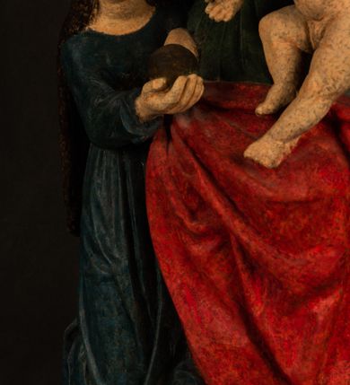 Zdjęcie nr 17: Rzeźba drążona przedstawiająca siedzącą św. Annę w towarzystwie klęczącej Marii oraz Dzieciątka Jezus. Anna ukazana frontalnie, z głową pochyloną nieznacznie w dół, obejmująca rękoma przedstawioną z prawej strony Marię oraz znajdujące się po lewej stronie Dzieciątko Jezus. Twarz świętej owalna o spokojnym wyrazie, z oczami skierowanymi w dół. Nos długi, prosty, na policzkach zaznaczony delikatny rumieniec. Anna ubrana jest w ciemnozieloną suknię przepasaną w talii, ciemnogranatową chustę zarzuconą na głowę, pod którą znajduje się biała podwika. Na ramiona i kolana postaci narzucony jest obszerny, czerwony płaszcz spod, którego widoczny jest ostro zakończony czubek brązowego buta św. Anny. Maria znajdująca się z lewej strony kompozycji została  przedstawiona jako młoda kobieta, klęcząca u stóp swojej matki i zwracająca się w kierunku siedzącego na kolanach Anny Dzieciątka Jezus. Owalną twarz Marii charakteryzuje wysokie czoło i cienkie, łukowato wygięte brwi. Długie, ciemne i lekko falowane włosy opadają na ramiona i plecy postaci. Maria swoją prawą rękę wspiera na kolanach Anny, lewą wyciąga przed siebie, podając Dzieciątku jabłko królewskie. Ubrana jest w ciemnogranatową suknię z długimi rękawami, spod której widoczne są bose stopy. Chrystus został ukazany jako nagi, ciemnowłosy chłopiec  o okrągłej twarzy z rumieńcem siedzący na kolanach św. Anny i wyciągający obie ręce w kierunku Marii. Rzeźba w pełni polichromowana.