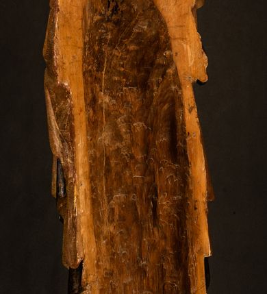 Zdjęcie nr 22: Przyścienna rzeźba Madonny z Dzieciątkiem jest z tyłu wydrążona. W tyle głowy Marii wbity jest hak służący do umocowania w ołtarzu. Matka Boska w całej postaci została ukazana w lekkim kontrapoście z charakterystycznym przegięciem w kształcie odwróconej litery &quot;S&quot;. Na prawej ręce trzyma Dzieciątko Jezus, lewą zaś ręką opuszczoną wzdłuż tułowia podtrzymuje nadgarstkiem fałdy płaszcza. Madonna ma pociągłą, zamyśloną twarz o jasnej karnacji, wysokie czoło i pucułowate, rumiane policzki. Ma prosty nos, migdałowe oczy oraz wydatne usta i podbródek. Jej głowę osadzoną na długiej szyi okalają zaczesane do tyłu brązowe włosy, widoczne spod osuwającej się chusty opadającej na ramiona dwoma festonami. Maria ubrana jest w złoconą suknię laserowaną ciepłą czerwienią oraz złocony płaszcz podbity srebrną podszewką z oliwkowo zielonym laserunkiem. Z przodu płaszcz drapowany jest w łukowate fałdy. Jedna z nich biegnie diagonalnie od prawej dłoni ku lewej stopie Madonny. Płaszcz po bokach postaci spływa rurkowatymi kaskadami. Maria na głowię ma wysoką, złotą koronę ze sterczynami o trójlistnych zakończeniach. Mały Jezus został ujęty w trzech czwartych z nieznacznie odchyloną głową do tyłu i skrzyżowanymi nóżkami. Lewą rękę kładzie na piersi matki, w prawej zaś trzyma złocone jabłko. Ma okrągłą, pucułowatą twarz o rumianych policzkach. Charakteryzuje ją prosty nosek, wydatne wargi i podbródek oraz wyraziste, szeroko otwarte oczy. Jego głowę z wysokim czołem okalają krótkie brązowe włosy. Ubrany jest w złocistą długą tunikę odsłaniającą fragmenty stóp.   